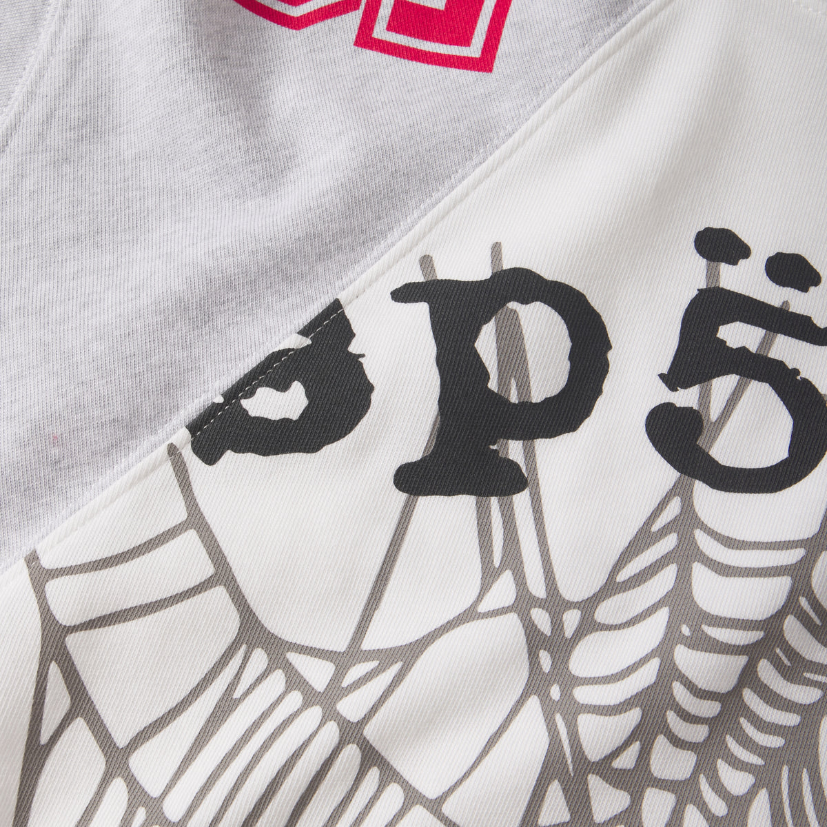 Cotton color-block tee featuring asymmetrical panels, collegiate-style red lettering, and a black spiderweb graphic print.