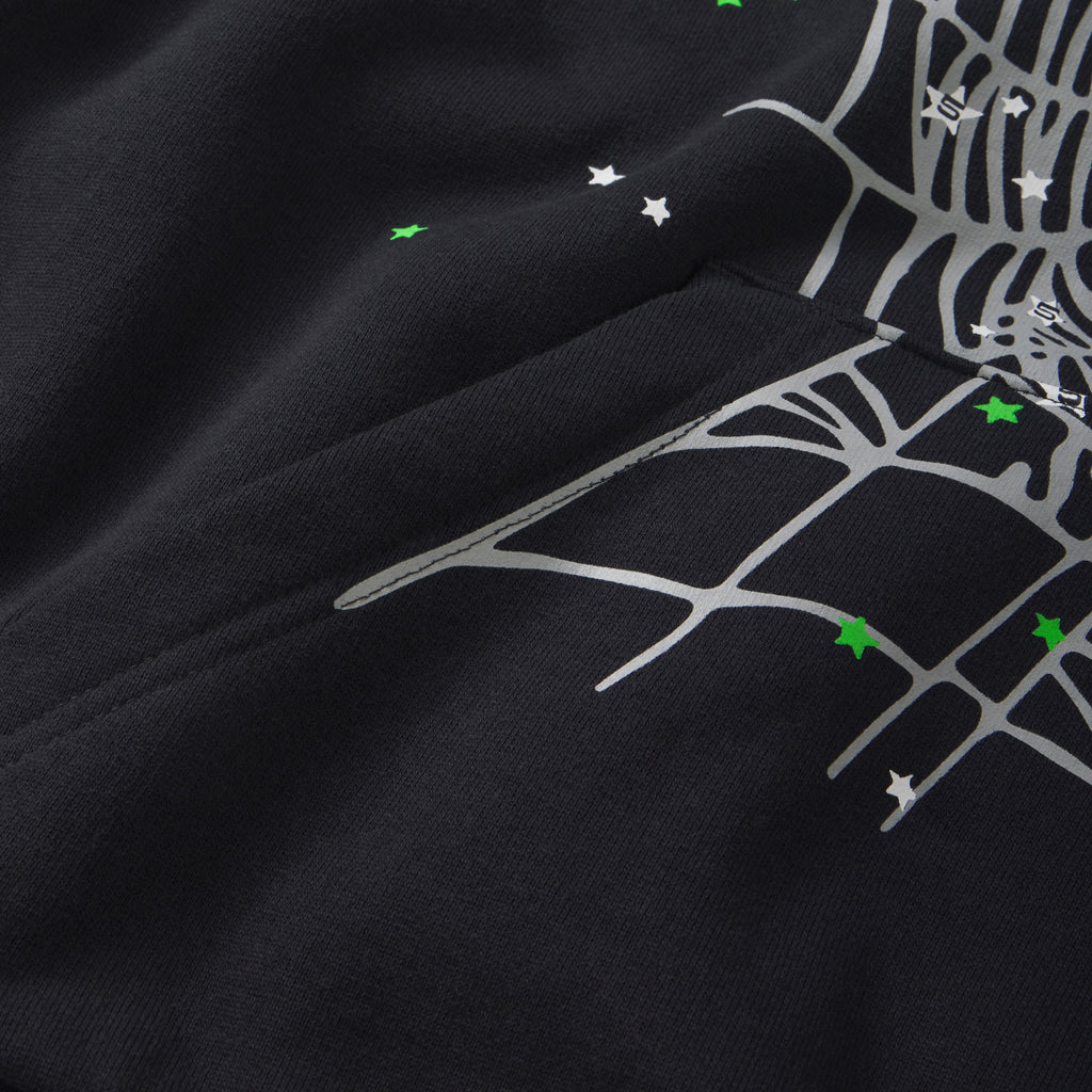 Black cotton fleece hoodie featuring a grey spider web graphic, scattered white and green star prints, and a kangaroo pocket.