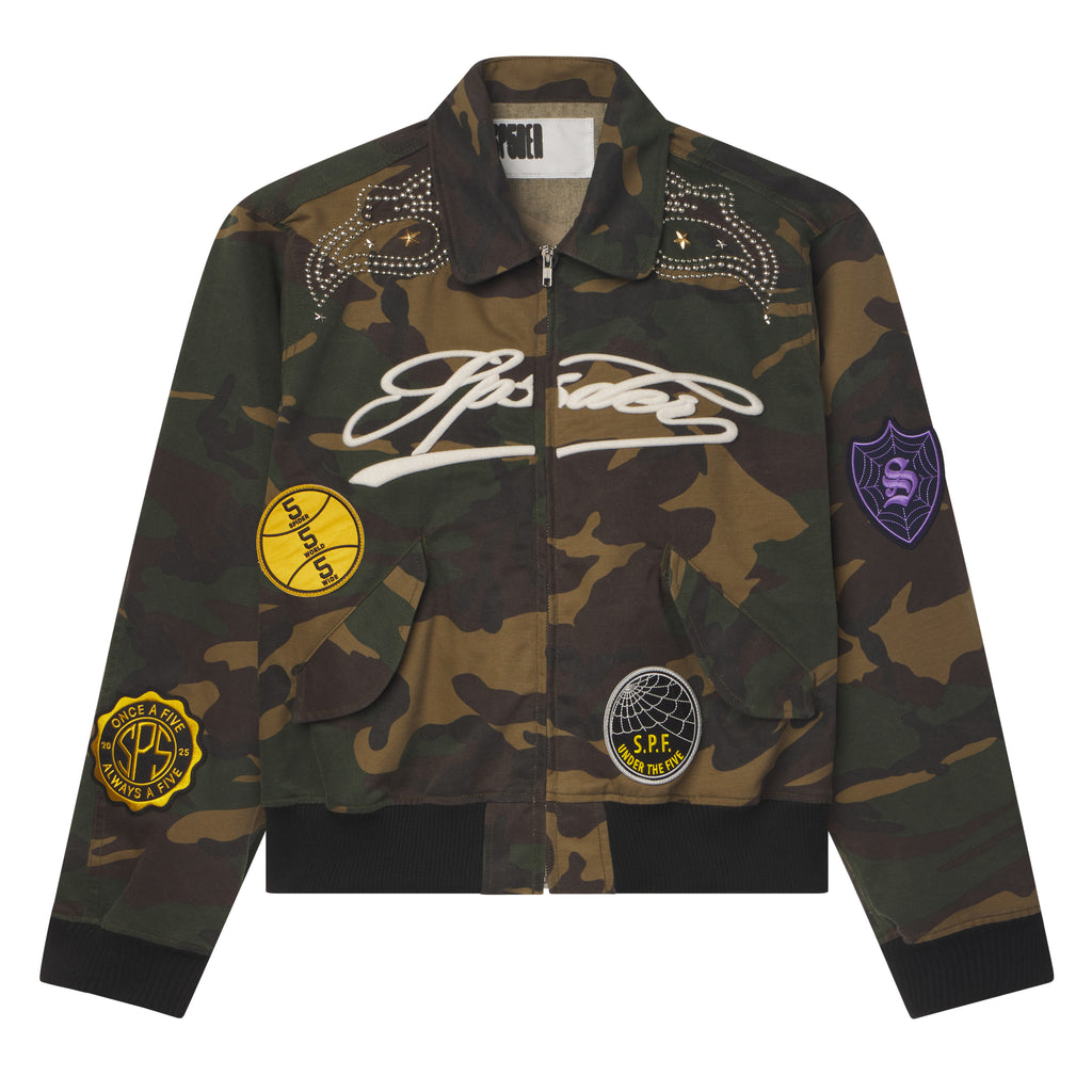 Camo cotton canvas bomber jacket with embroidered script, colorful graphic patches, and studded shoulder detailing.