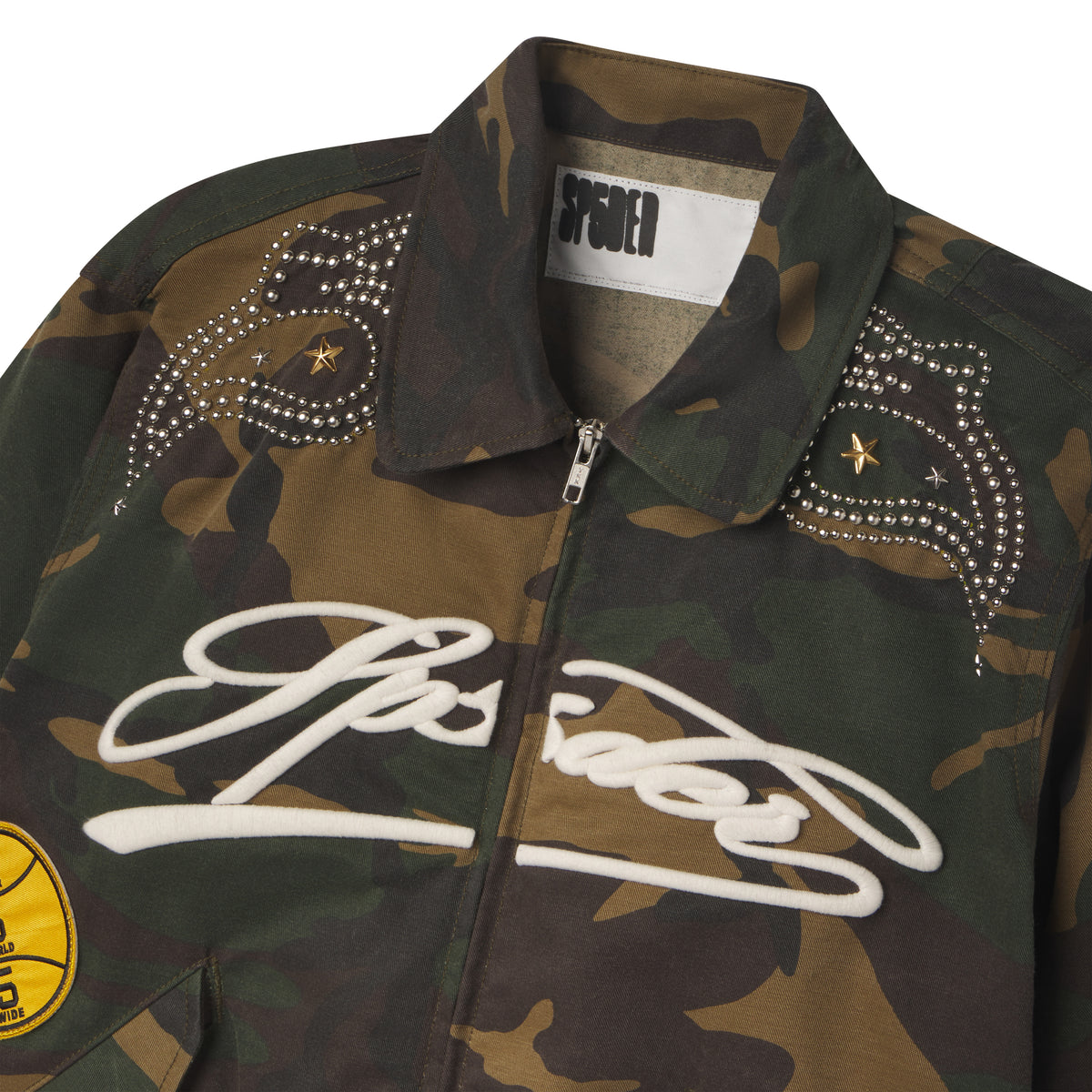 Camo cotton canvas bomber jacket with embroidered white script, studded shoulder detailing, and graphic patches.