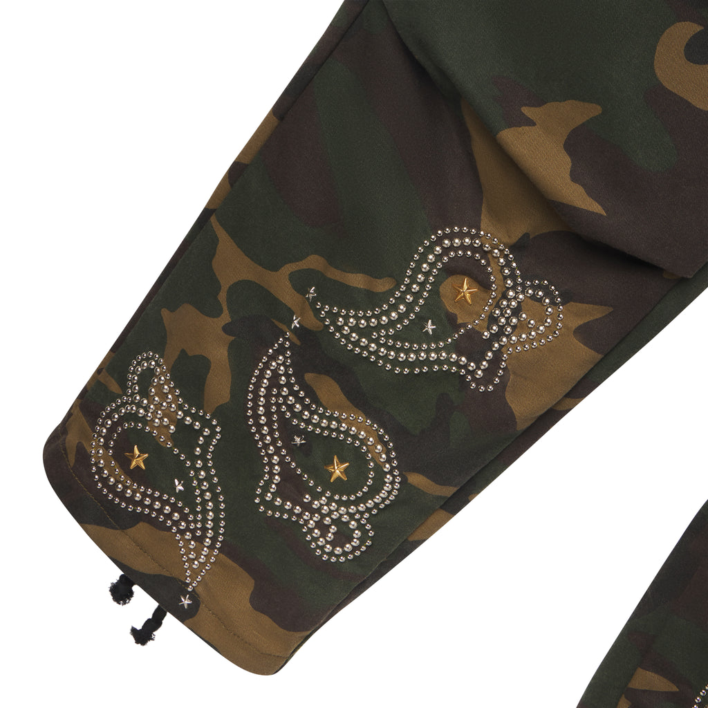 Cotton canvas camo cargo pants featuring intricate studded paisley graphic designs and gold star accents at the hem.