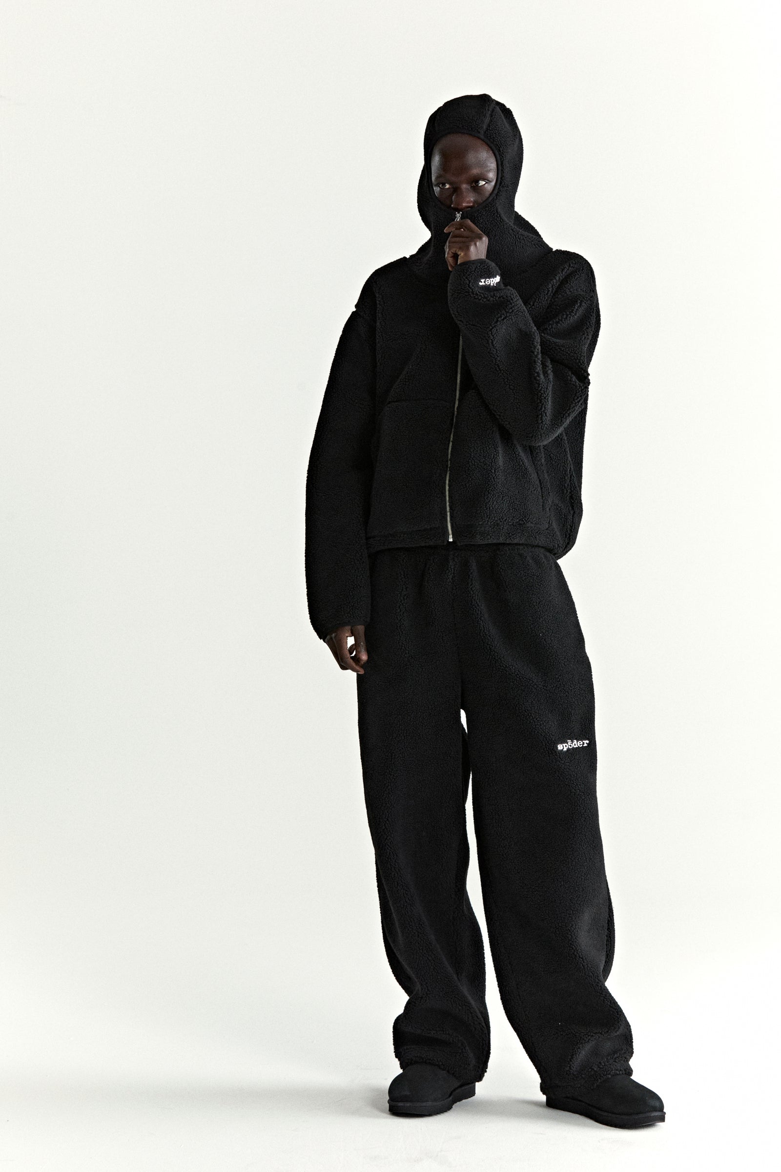 Black teddy fleece zip-up jacket with hood and matching sweatpants, worn by a model.