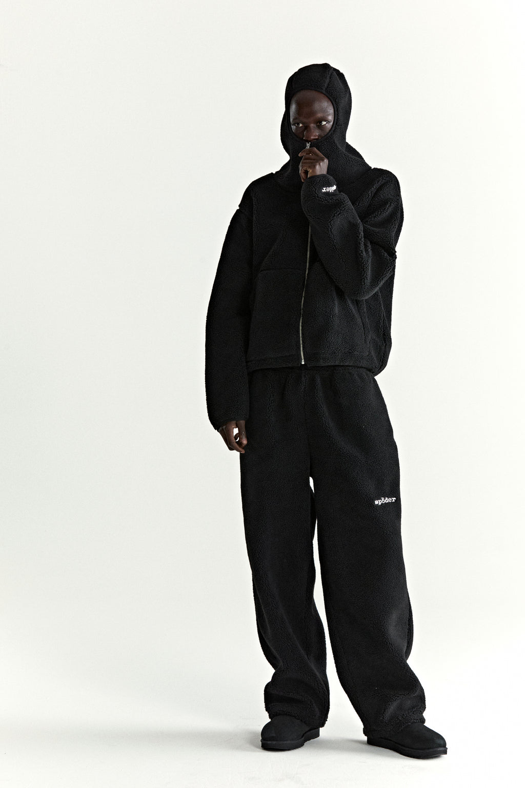 Black teddy fleece zip-up jacket with hood and matching sweatpants, worn by a model.