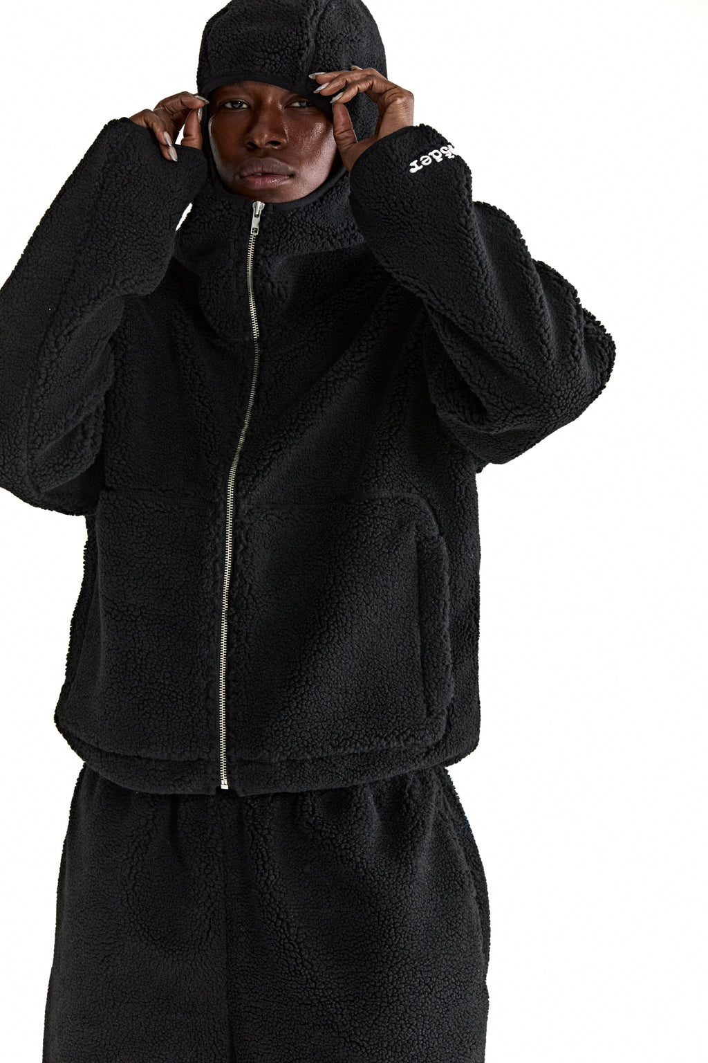 Black teddy fleece zip-up jacket with hood, welt pockets, and white logo on sleeve.