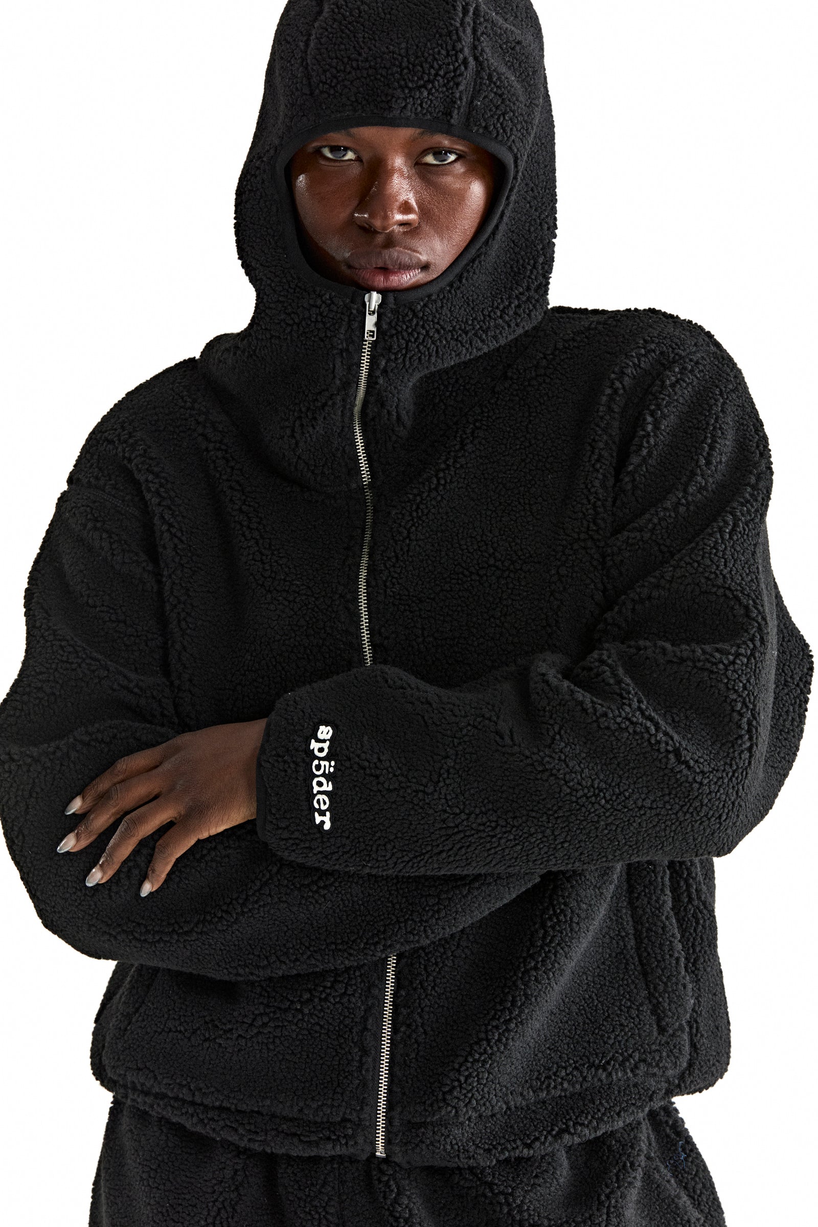Black sherpa fleece zip-up hooded jacket with rubberized logo patch on wrist.