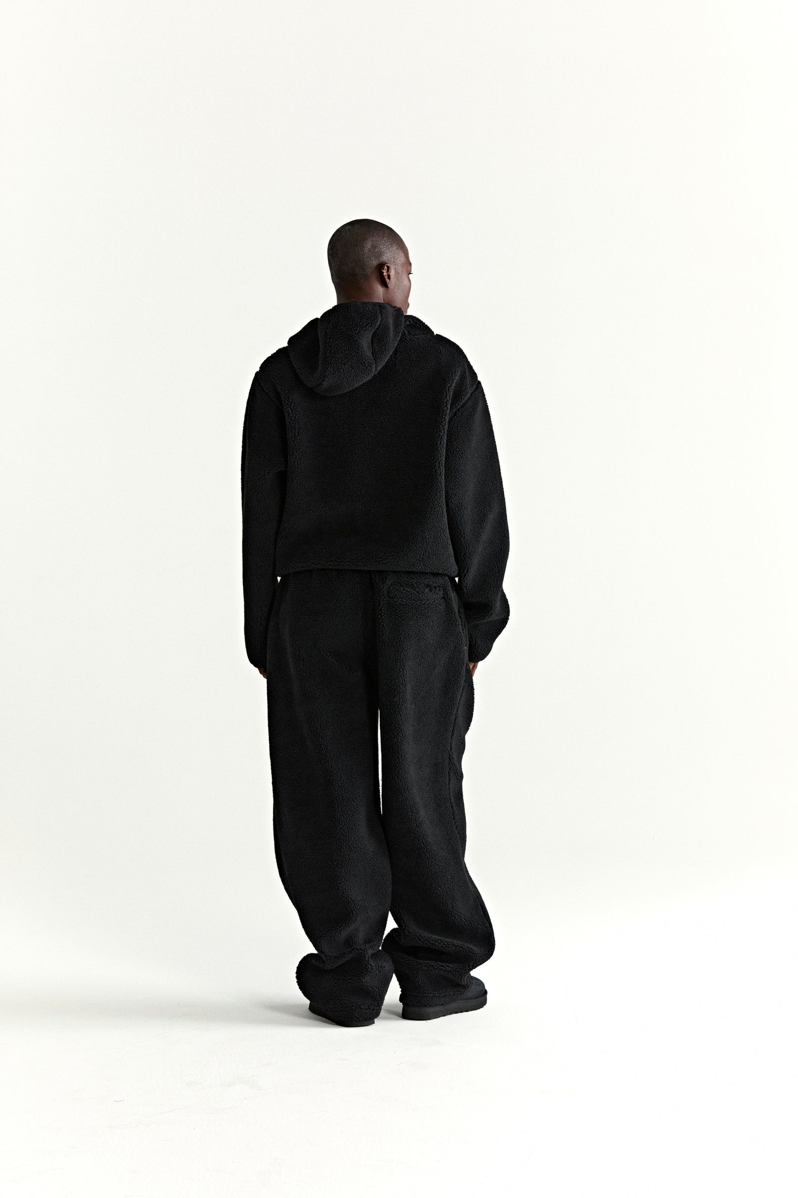 Black teddy fleece zip-up hooded jacket and matching pants, seen from behind.