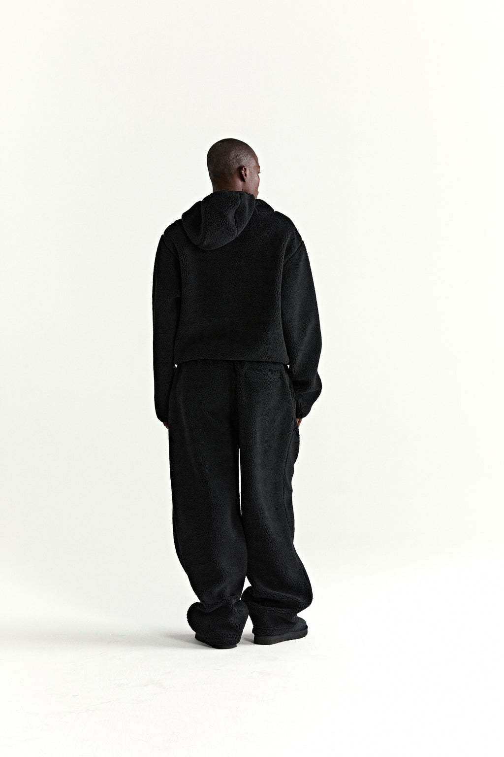 Black teddy fleece zip-up hooded jacket and matching pants, seen from behind.