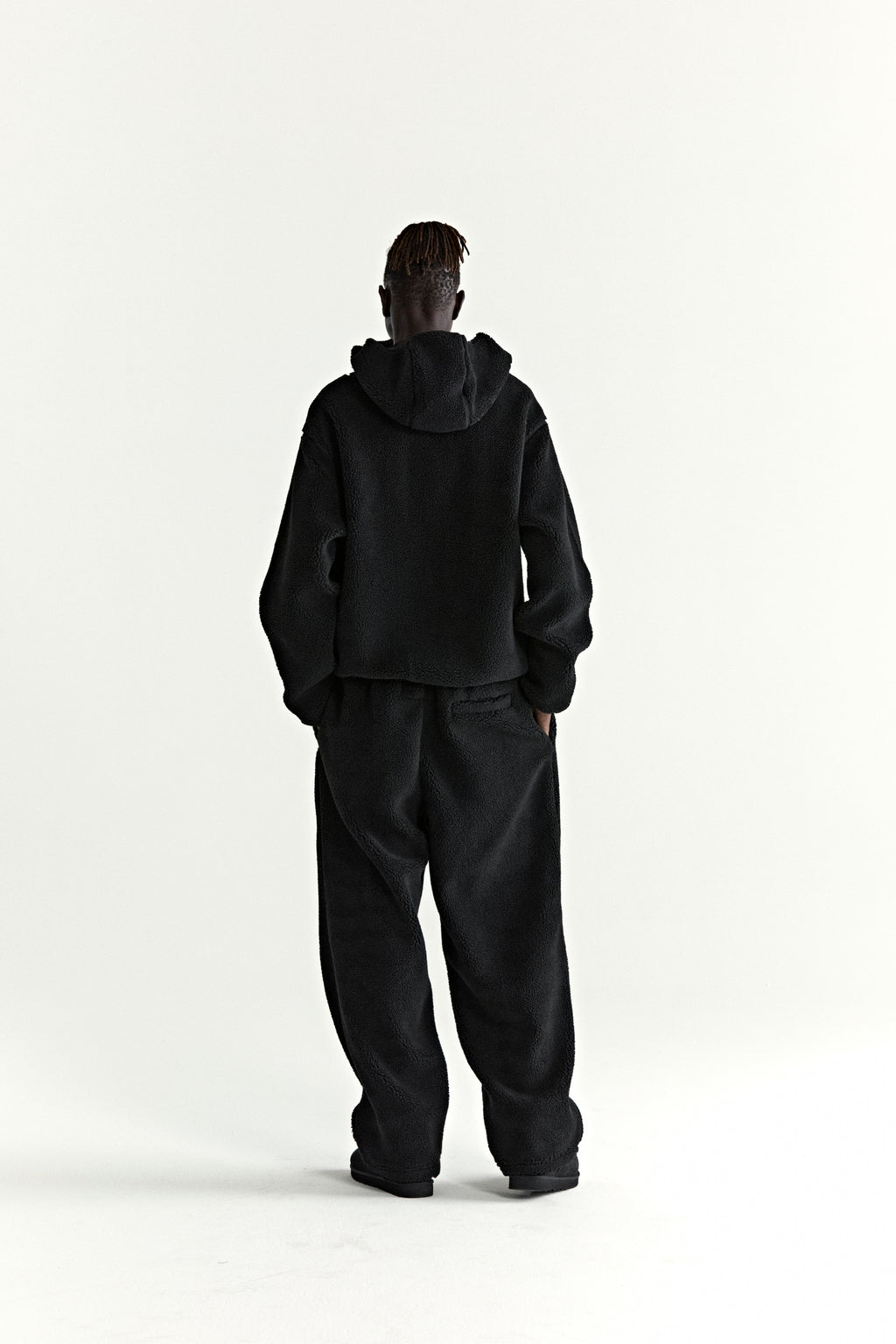 Black teddy fleece zip-up hoodie and matching sweatpants on a model from behind.