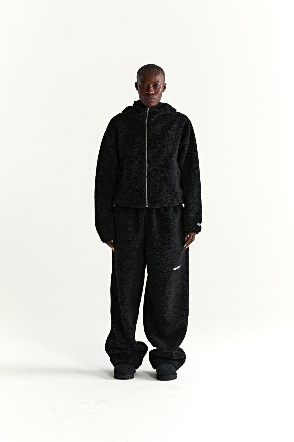 Black teddy fleece zip-up jacket with hood and matching sweatpants, worn by a model.