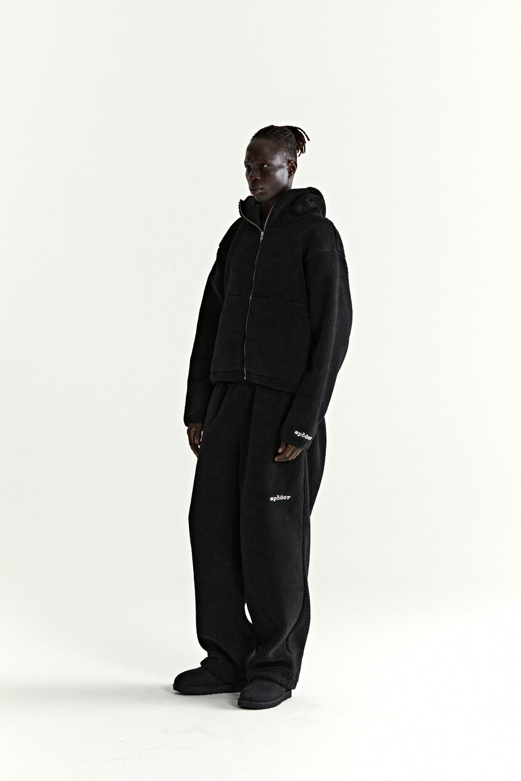 Black teddy fleece zip-up hooded jacket and matching pants with white logo patches.