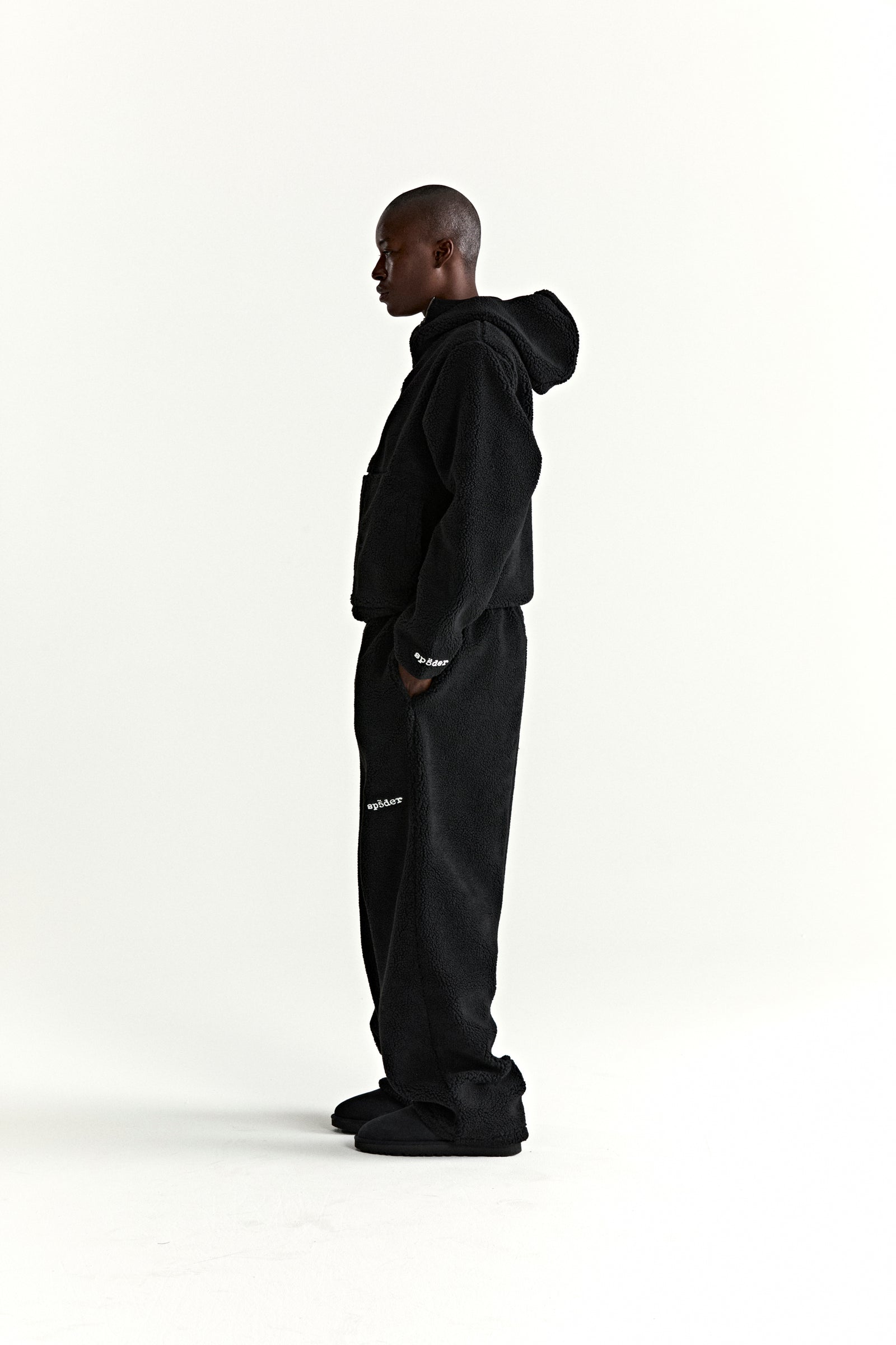 Black teddy fleece zip-up hoodie and matching sweatpants on a model, side view.