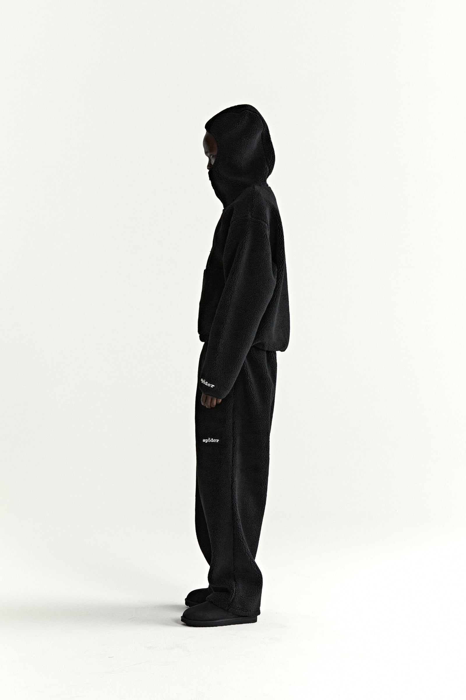 Black teddy fleece zip-up hoodie and matching pants with white "spider" logo on sleeve and leg.