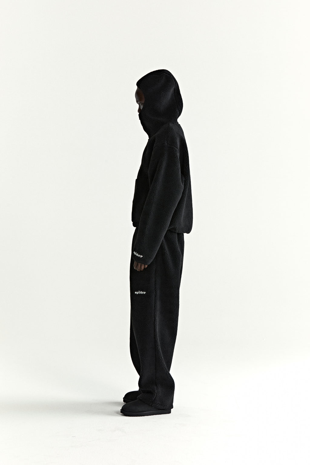 Black teddy fleece zip-up hoodie and matching pants with white "spider" logo on sleeve and leg.