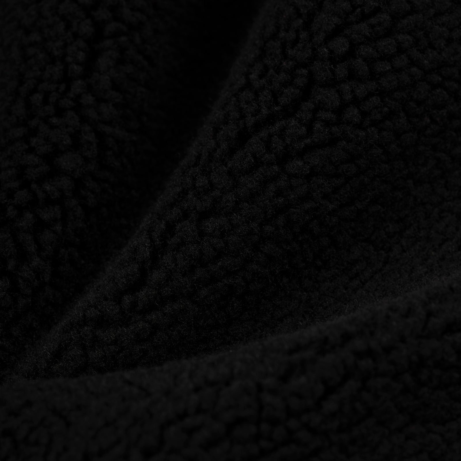Close-up of black teddy sherpa fleece fabric, showing its soft, textured material.
