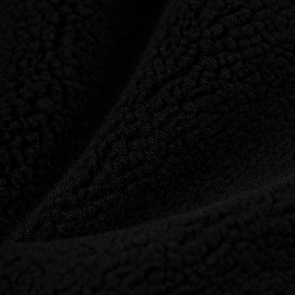 Close-up of black teddy sherpa fleece fabric, showing its soft, textured material.