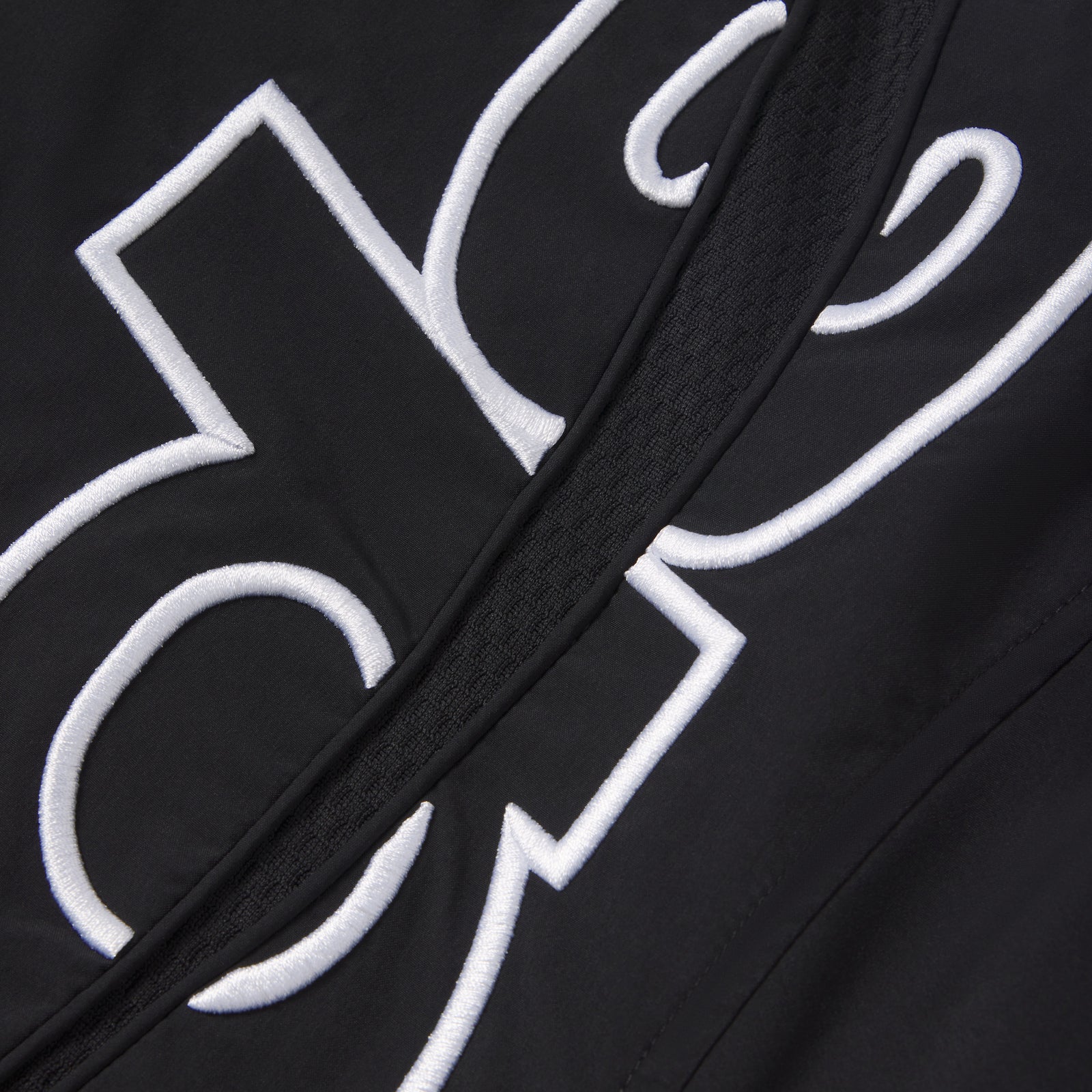 Black nylon track jacket featuring white embroidered graphic design and a full zip closure with a textured center panel.