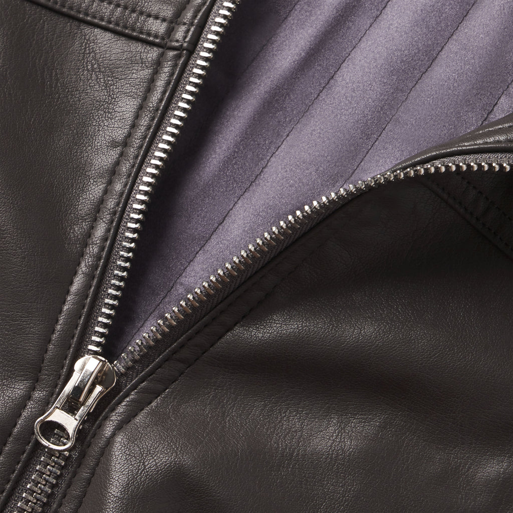 Close-up of a black faux leather hooded jacket featuring a metallic front zipper and grey interior lining.