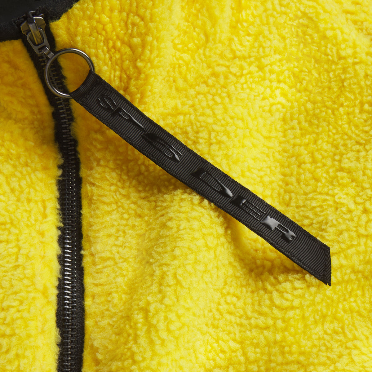 Bright yellow textured fleece jacket with a black full-length zipper and branded ring pull featuring graphic SP5DER lettering.
