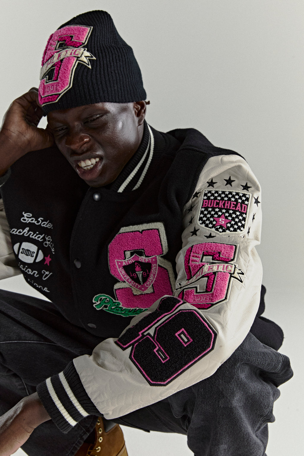 DIVISION 5 Varsity Jacket: black wool body, cream leather sleeves with debossed web design, pink and black patches.