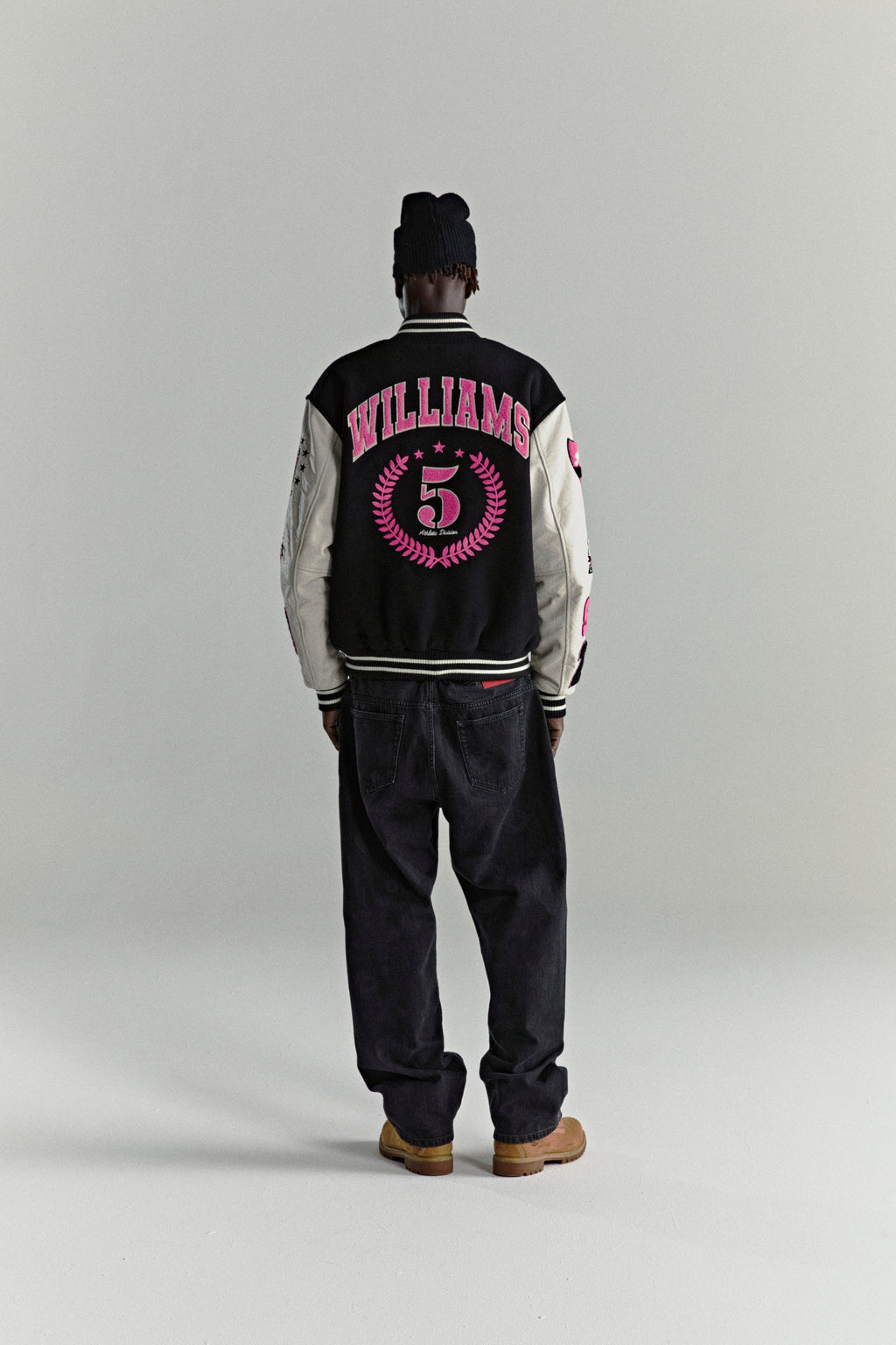 DIVISION 5 Varsity Jacket: Black wool body, white leather sleeves with debossed web, pink patches, striped ribbing.