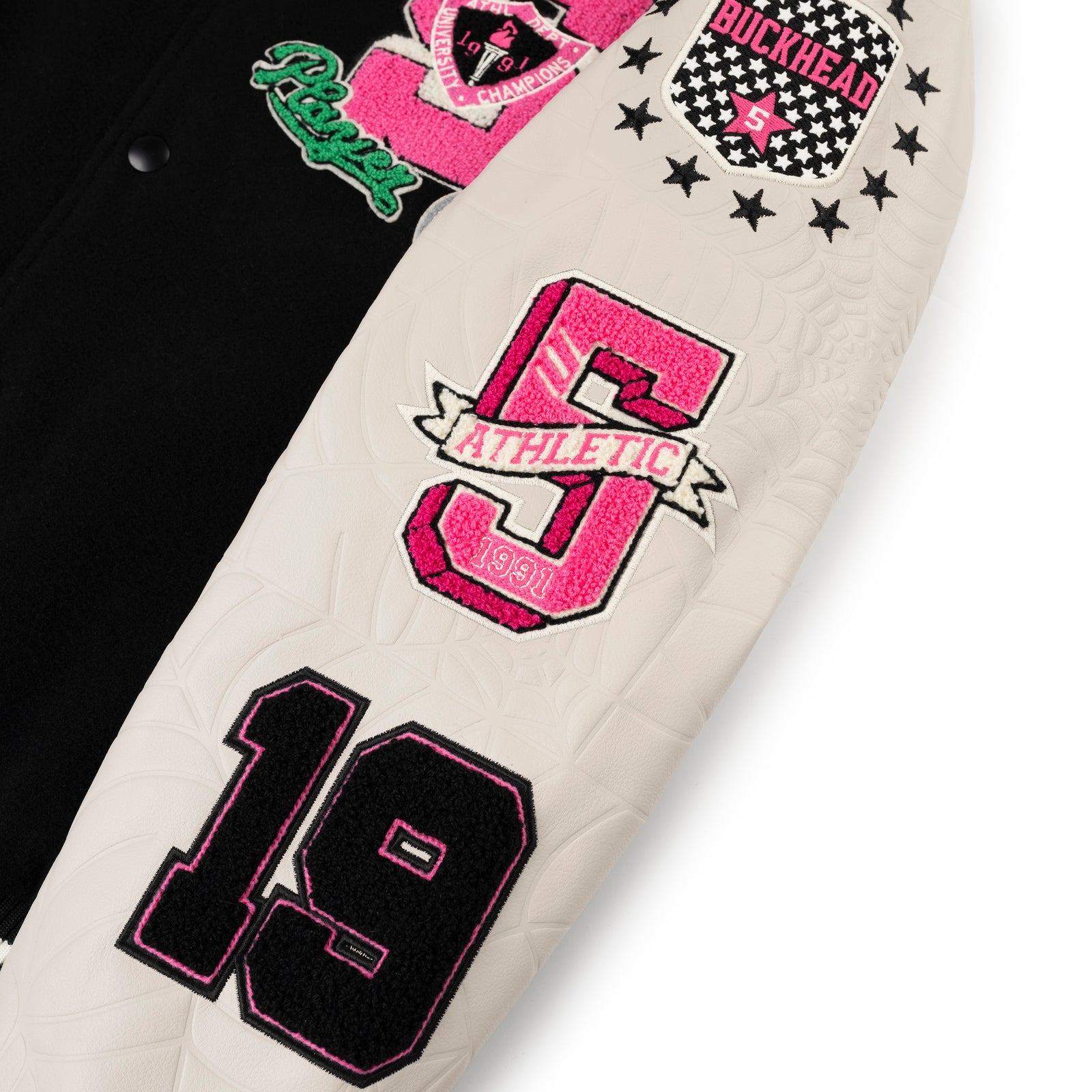 Black wool varsity jacket with white leather sleeves, debossed web design, and pink/black embroidered patches.