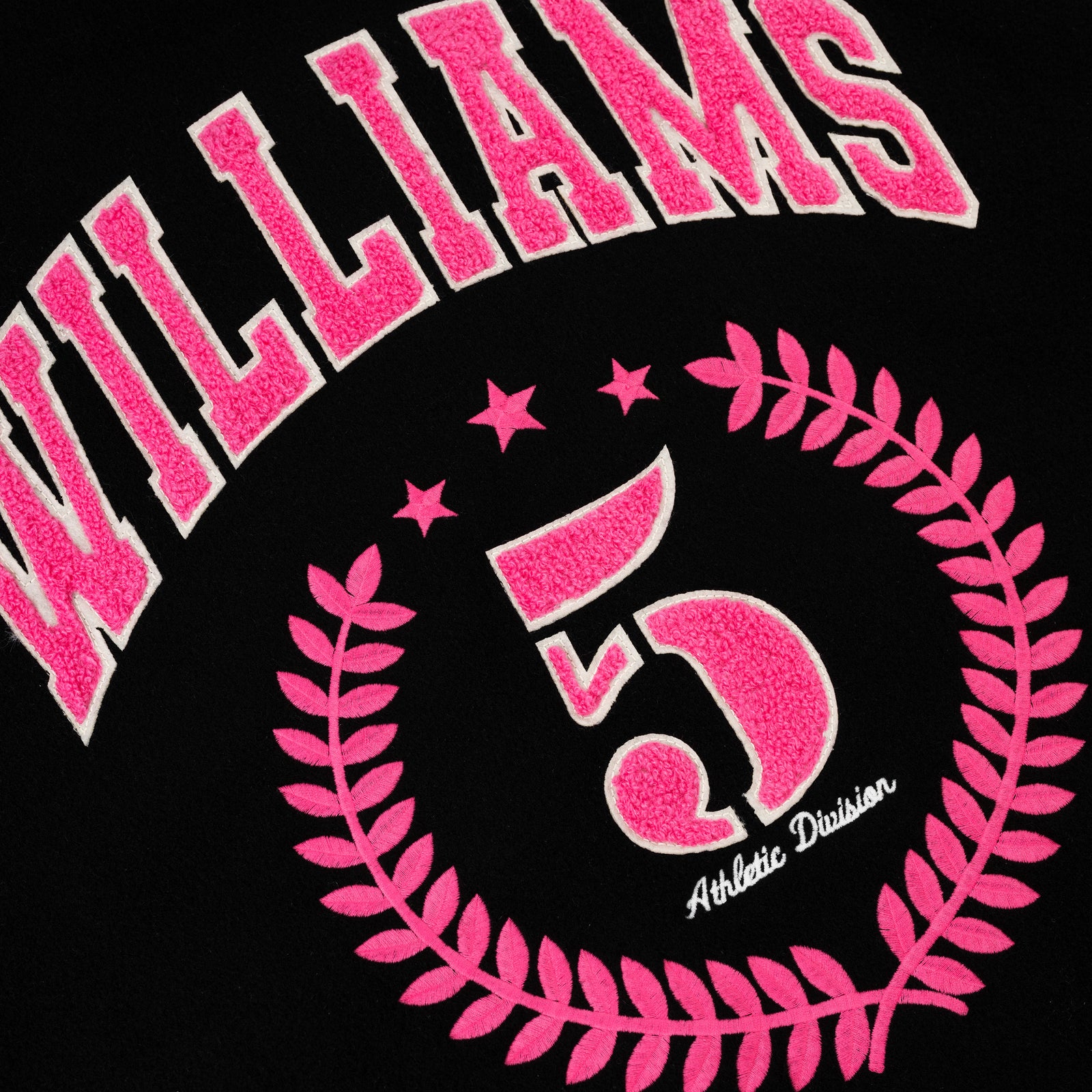 Black varsity jacket with pink "WILLIAMS" lettering, "5" in a laurel wreath, and "Athletic Division" embroidery.