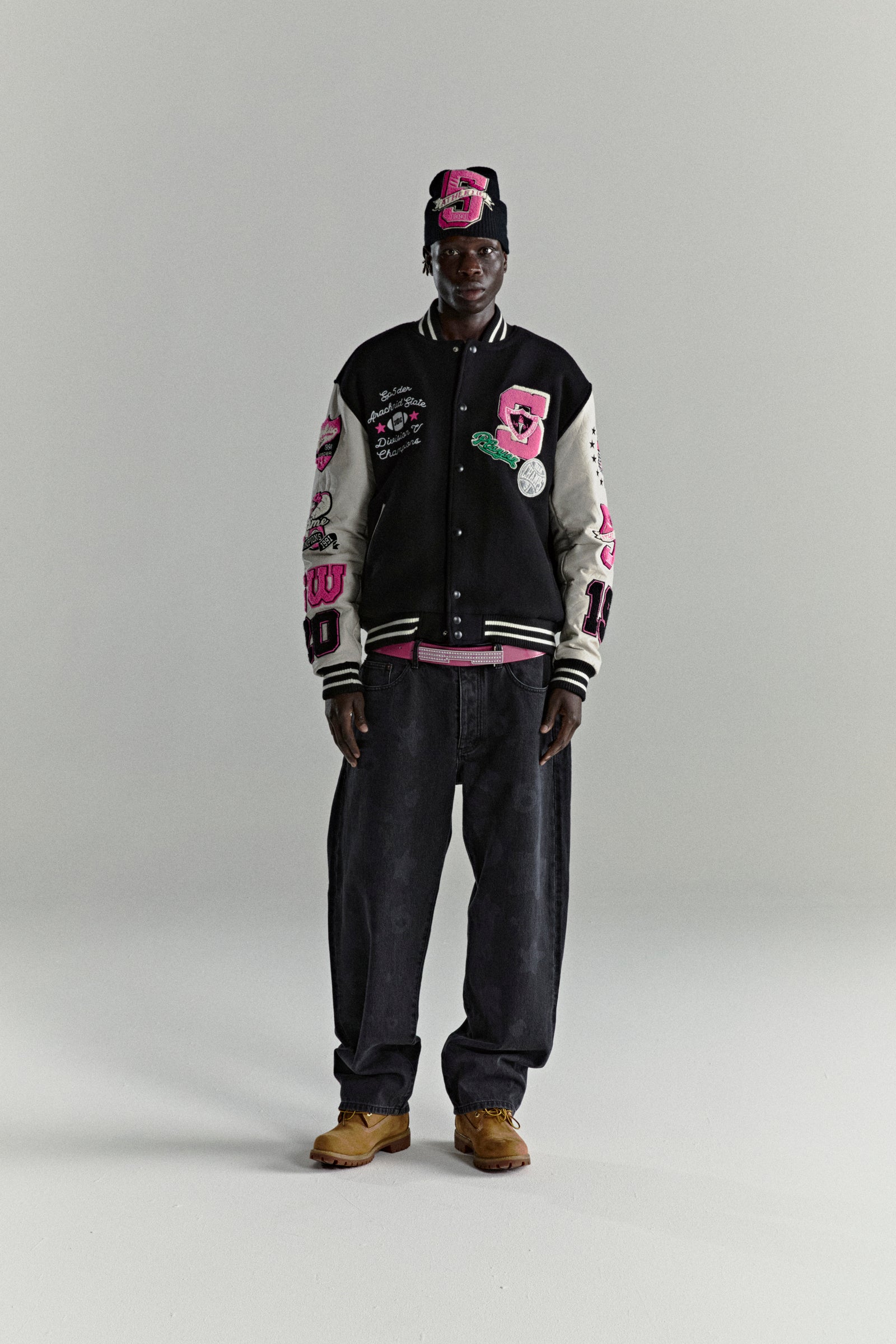 DIVISION 5 Varsity Jacket: Black wool body, leather sleeves with debossed web, embroidered patches, striped ribbed trim.