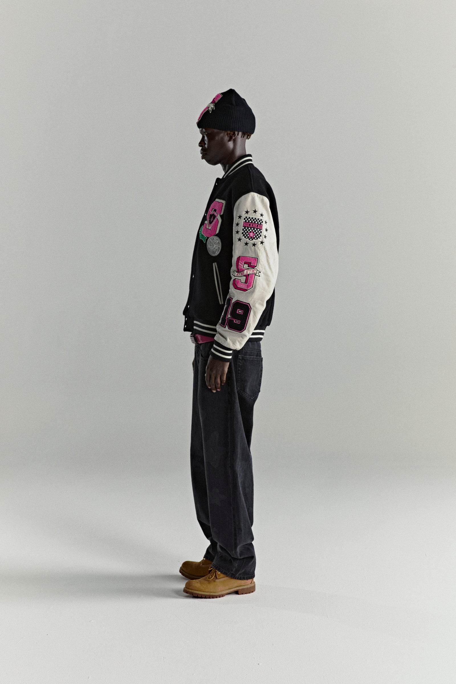 DIVISION 5 Varsity Jacket: black wool body, white leather sleeves with debossed web design, pink patches.