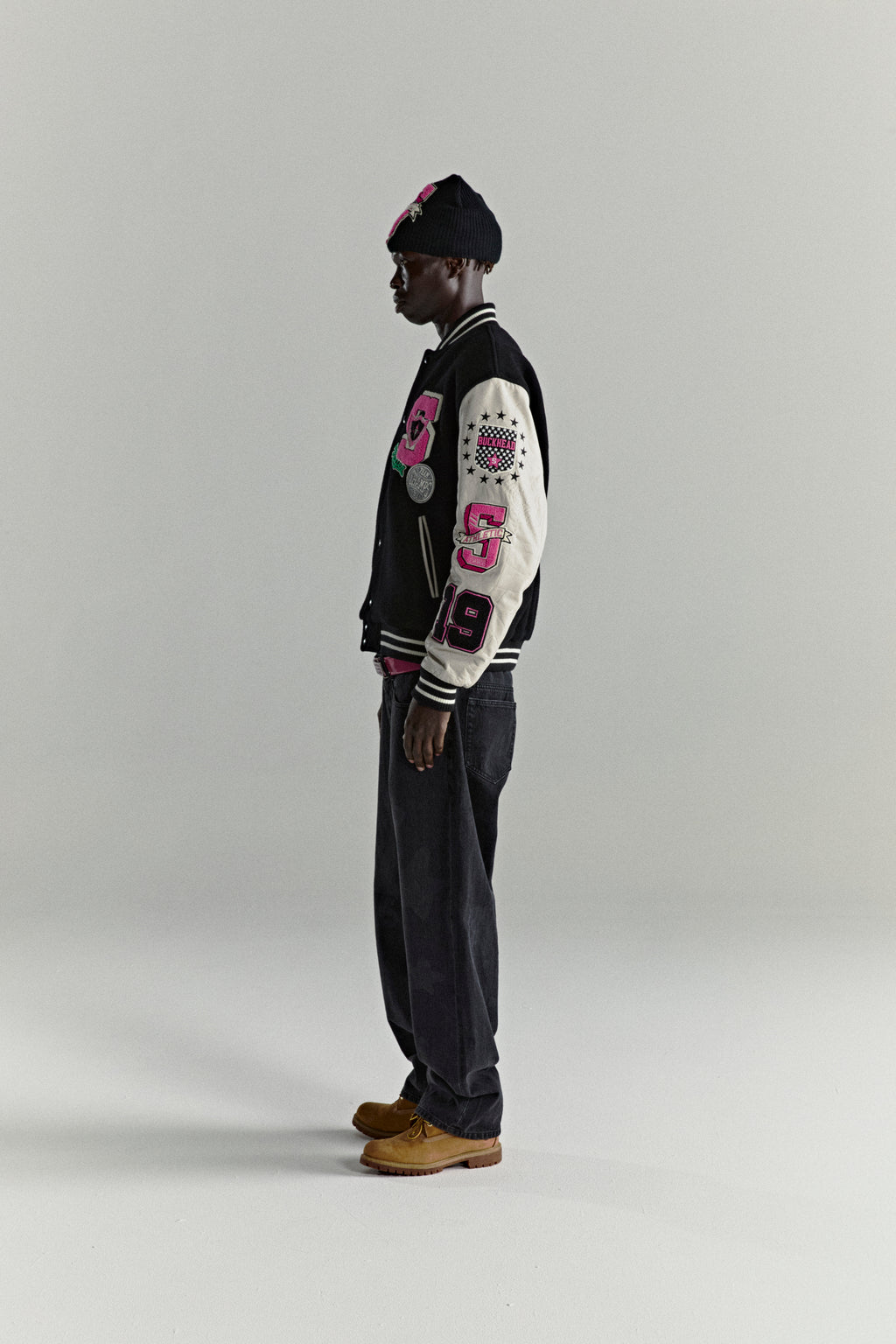 DIVISION 5 Varsity Jacket: black wool body, white leather sleeves with debossed web design, pink patches.