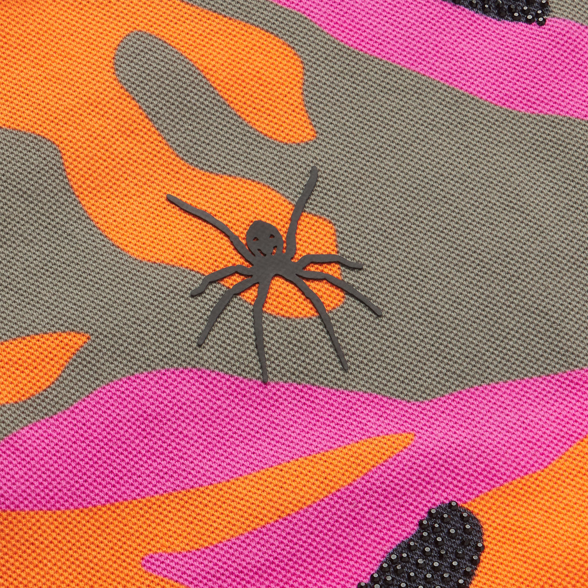 Cotton polo with orange, pink, and grey camo graphic print, black spider logo, and rhinestone embellishments.