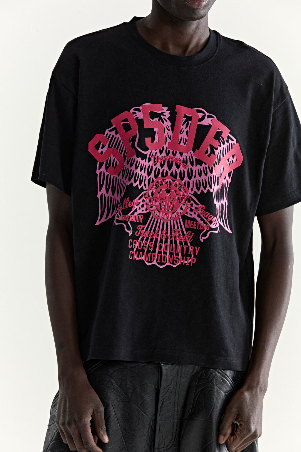 Black slub jersey tee with a vibrant pink "CROSS COUNTRY" eagle graphic print.