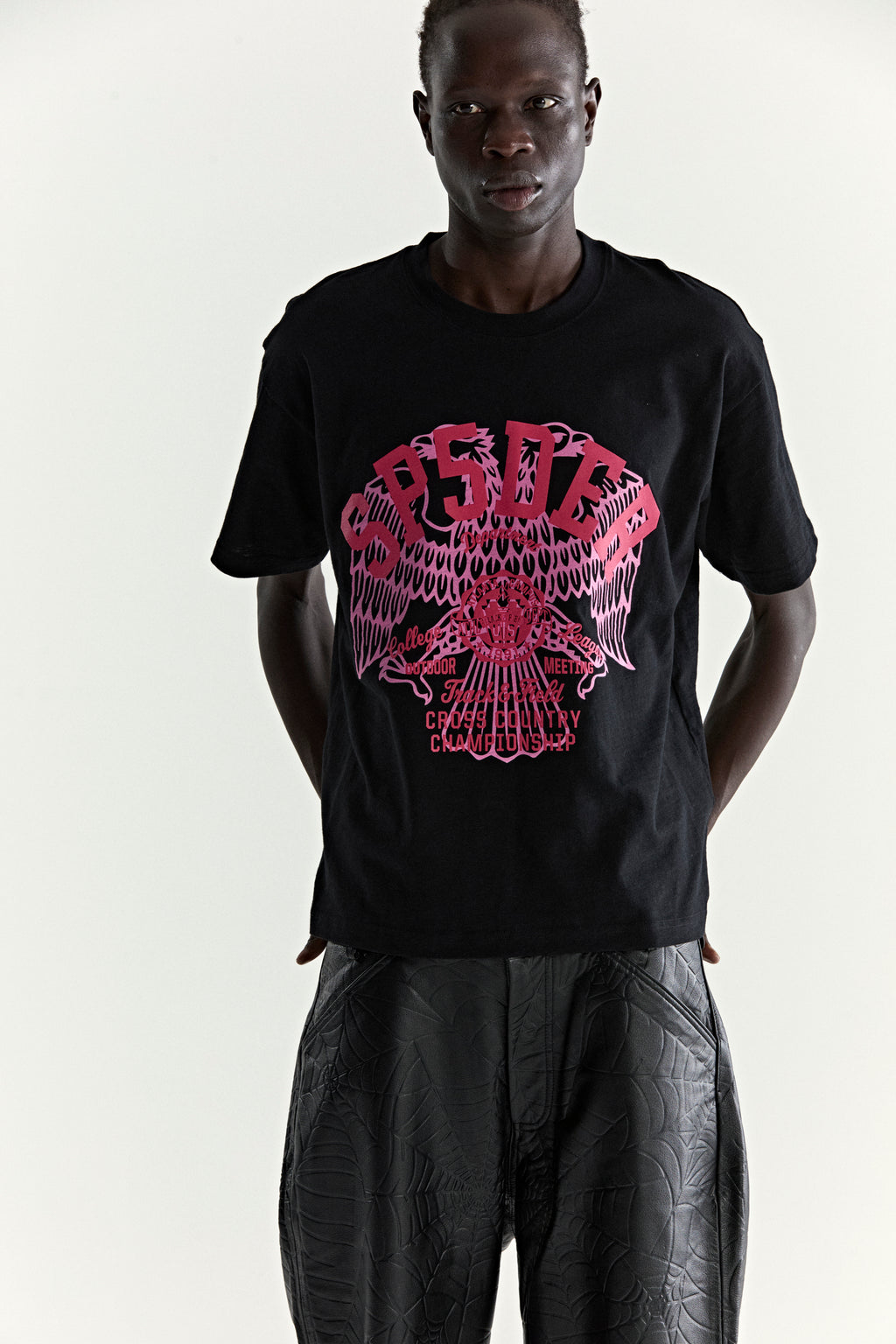 Black slub jersey tee with a vibrant pink graphic print featuring an eagle and "CROSS COUNTRY" text.