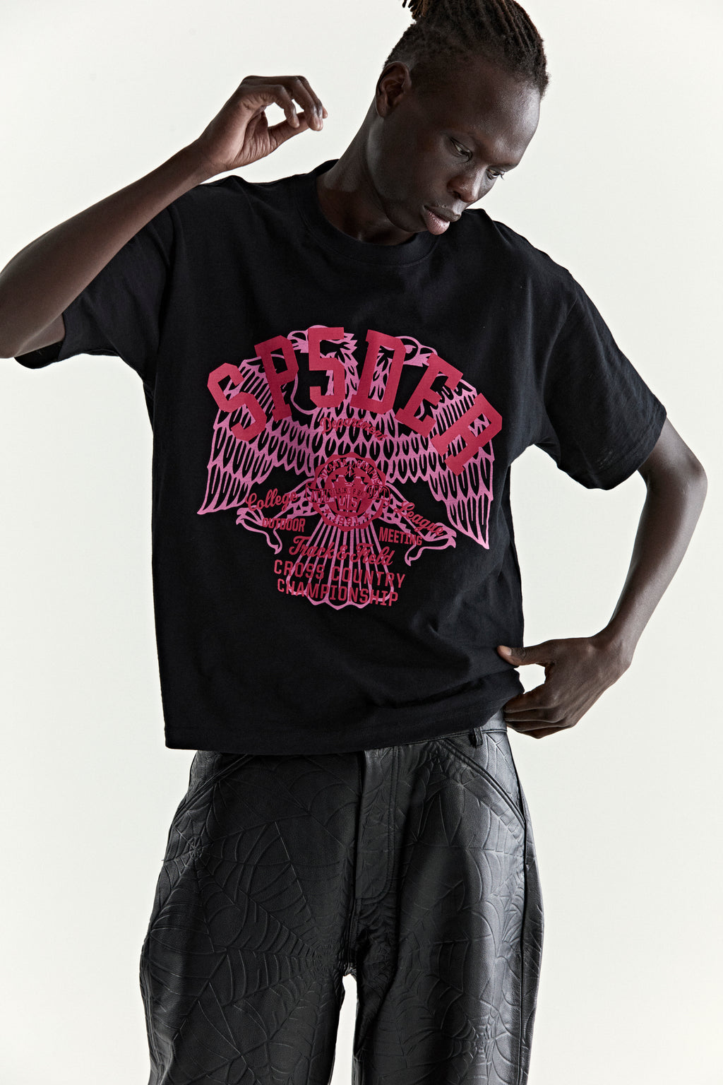 Black slub jersey tee with a large pink graphic print of an eagle and "CROSS COUNTRY" text.