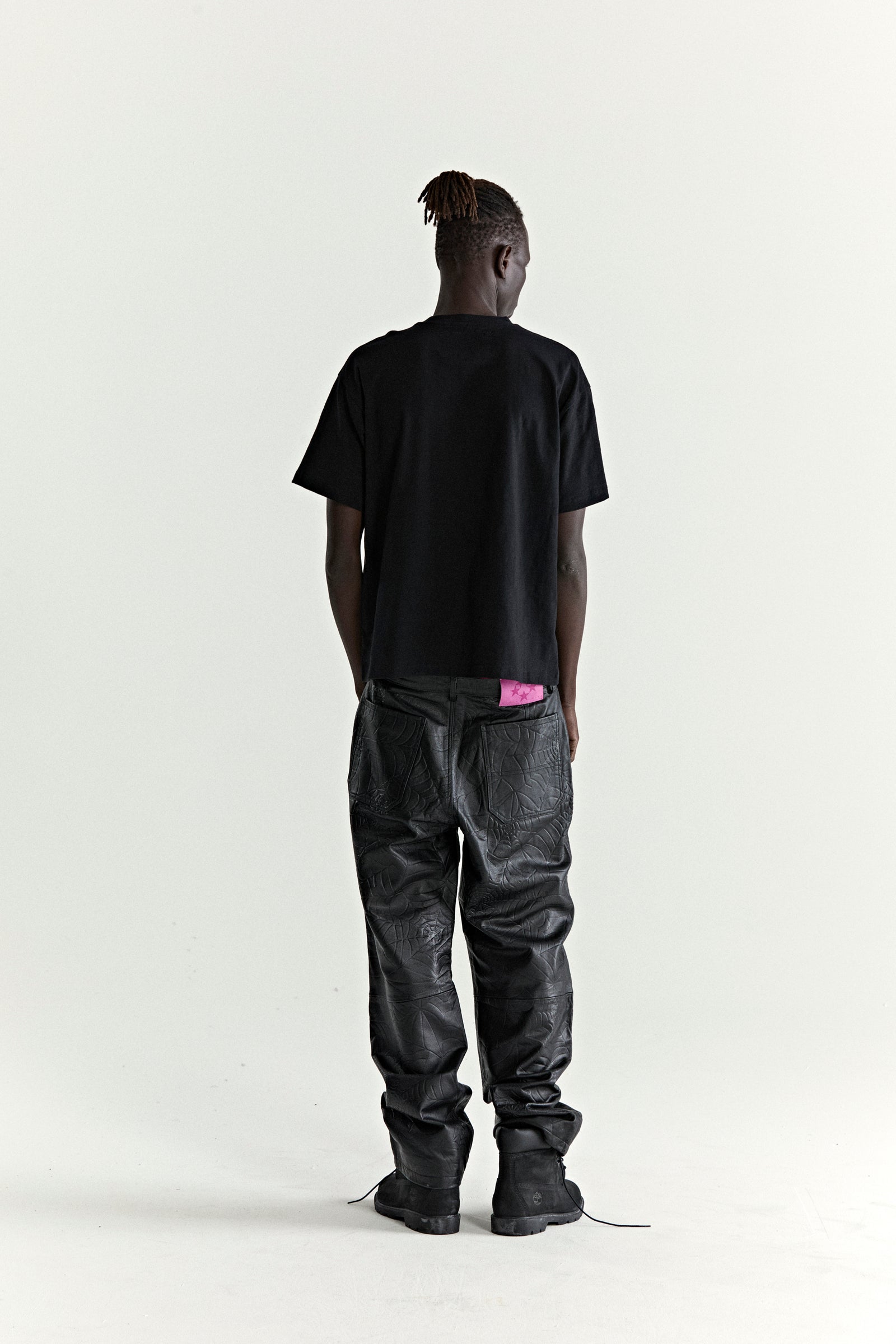 Black slub jersey tee with graphic print, paired with black textured pants and boots.