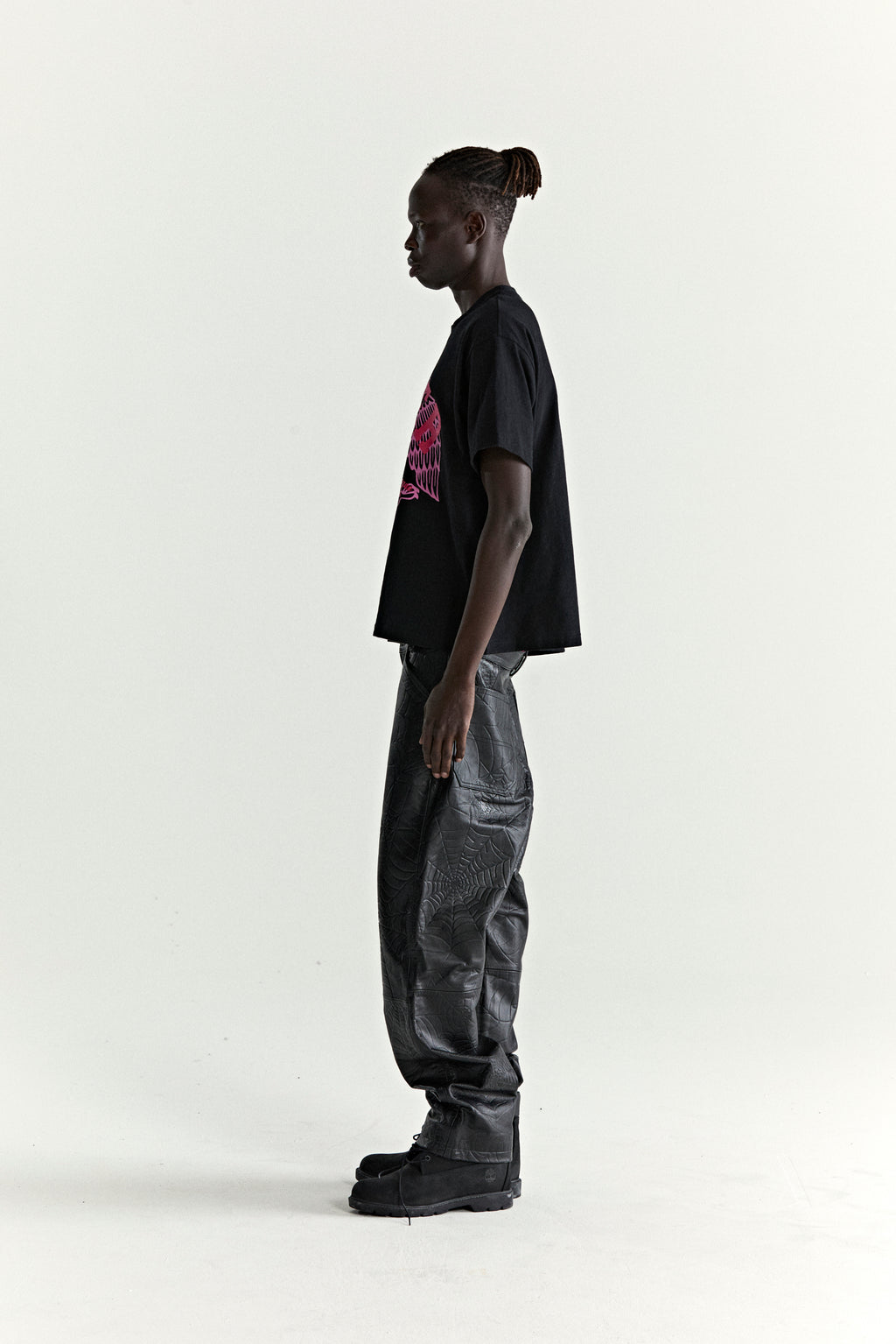 Black slub jersey tee with red graphic print, paired with black textured pants and boots.