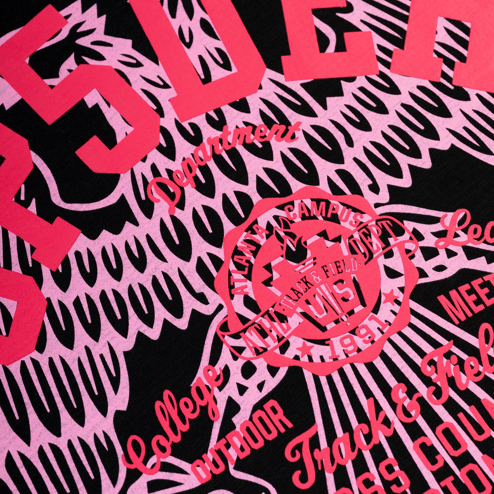Black slub jersey tee with vibrant pink "CROSS COUNTRY" graphic print and track & field emblem.