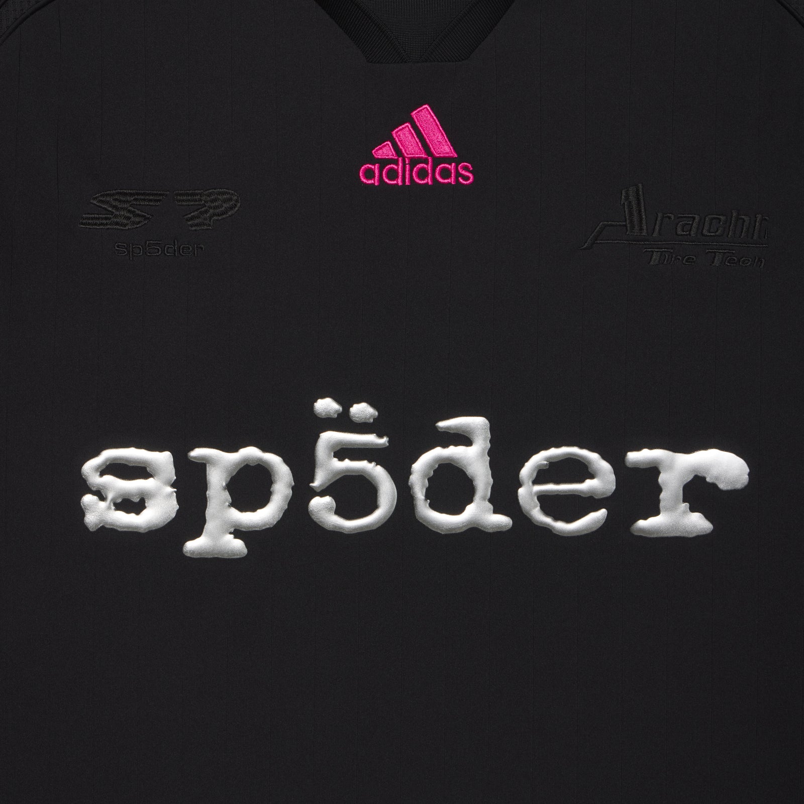 Black polyester SP5DER football jersey with pink adidas logo, tonal chest graphics, and reflective SP5DER graphic print.