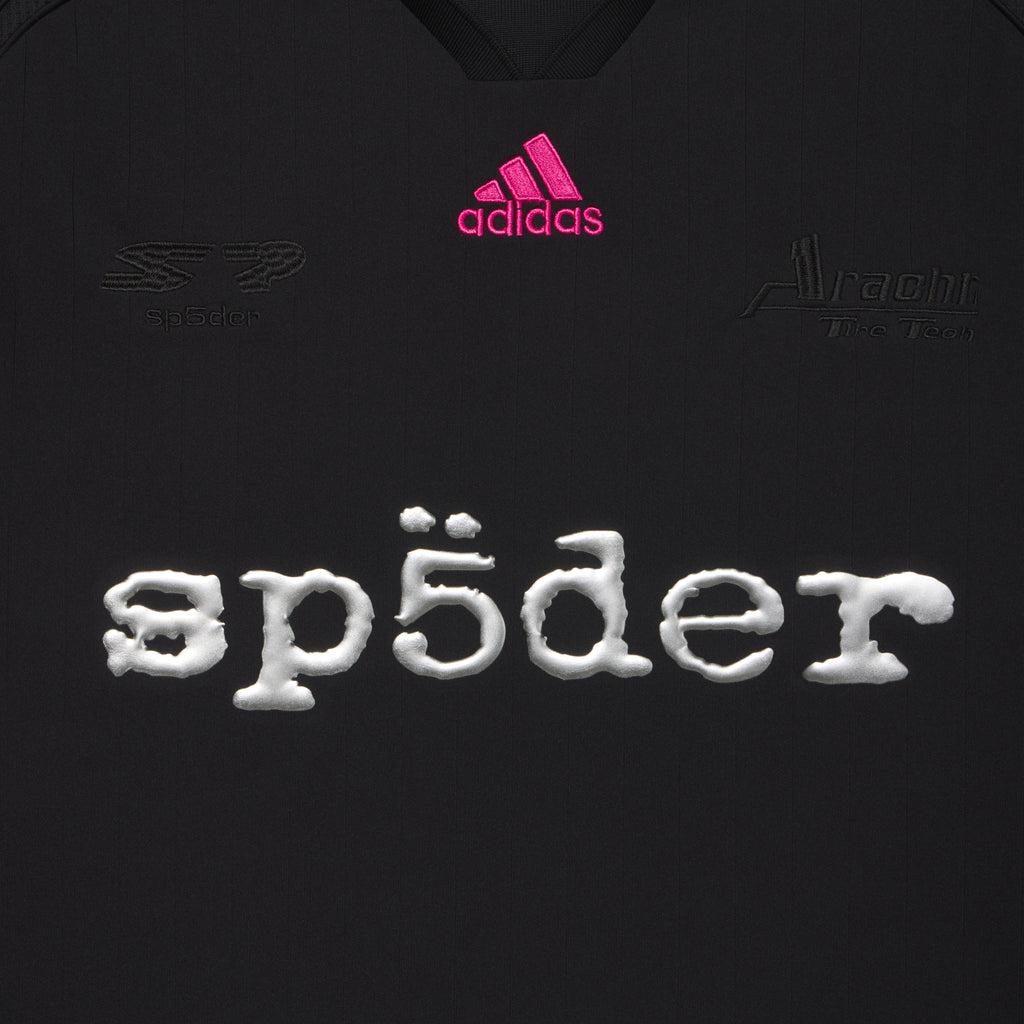 Black polyester SP5DER football jersey with pink adidas logo, tonal chest graphics, and reflective SP5DER graphic print.