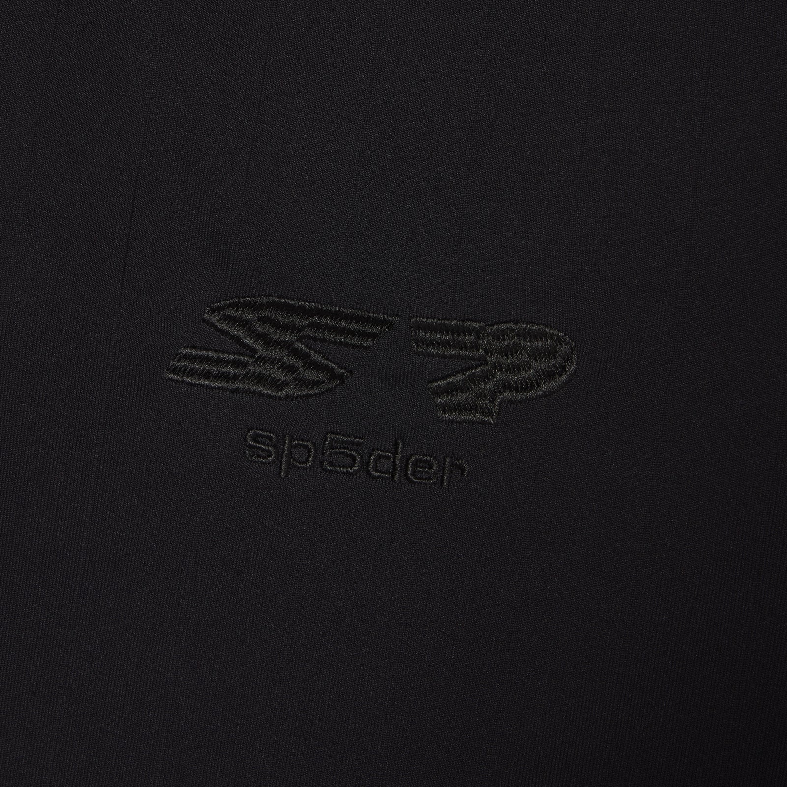 Black polyester SP5DER FOOTBALL JERSEY with reflective SP5DER graphic design at front.