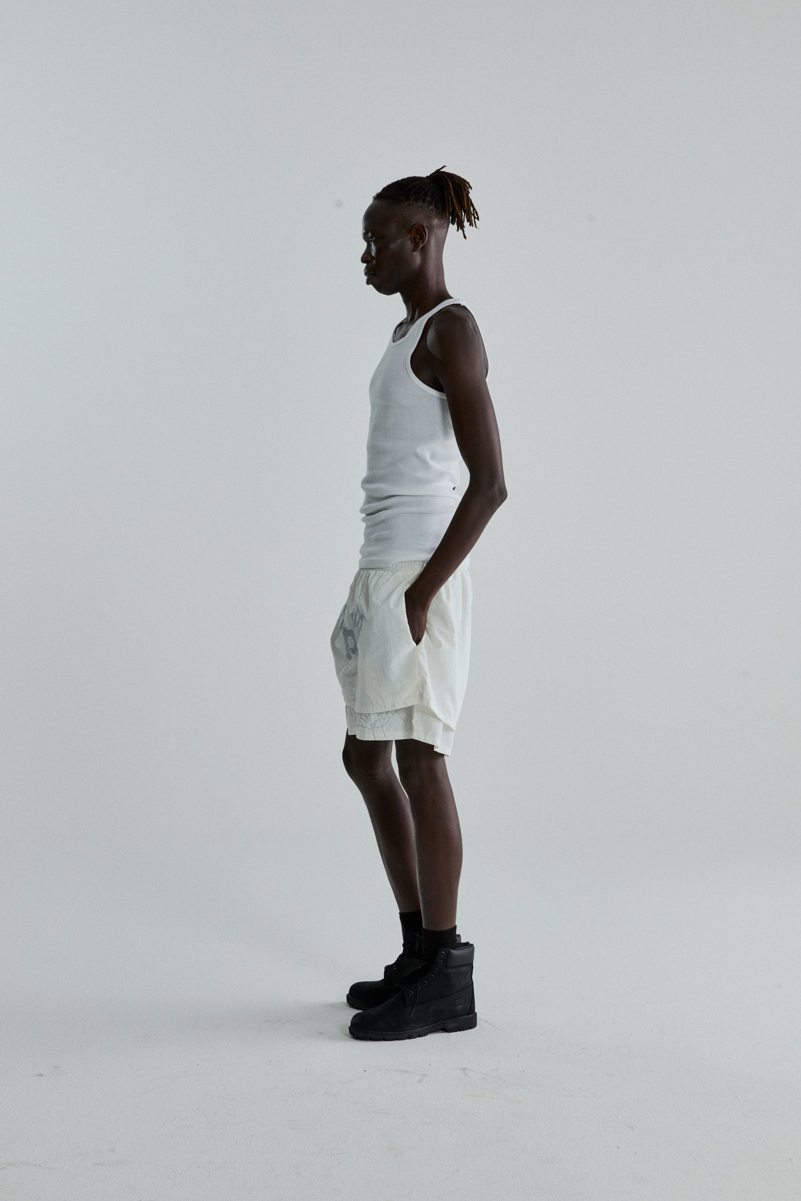 Model in white OG WEB Double Layer Short with high-low design, OG SP5DER text, and star print.
