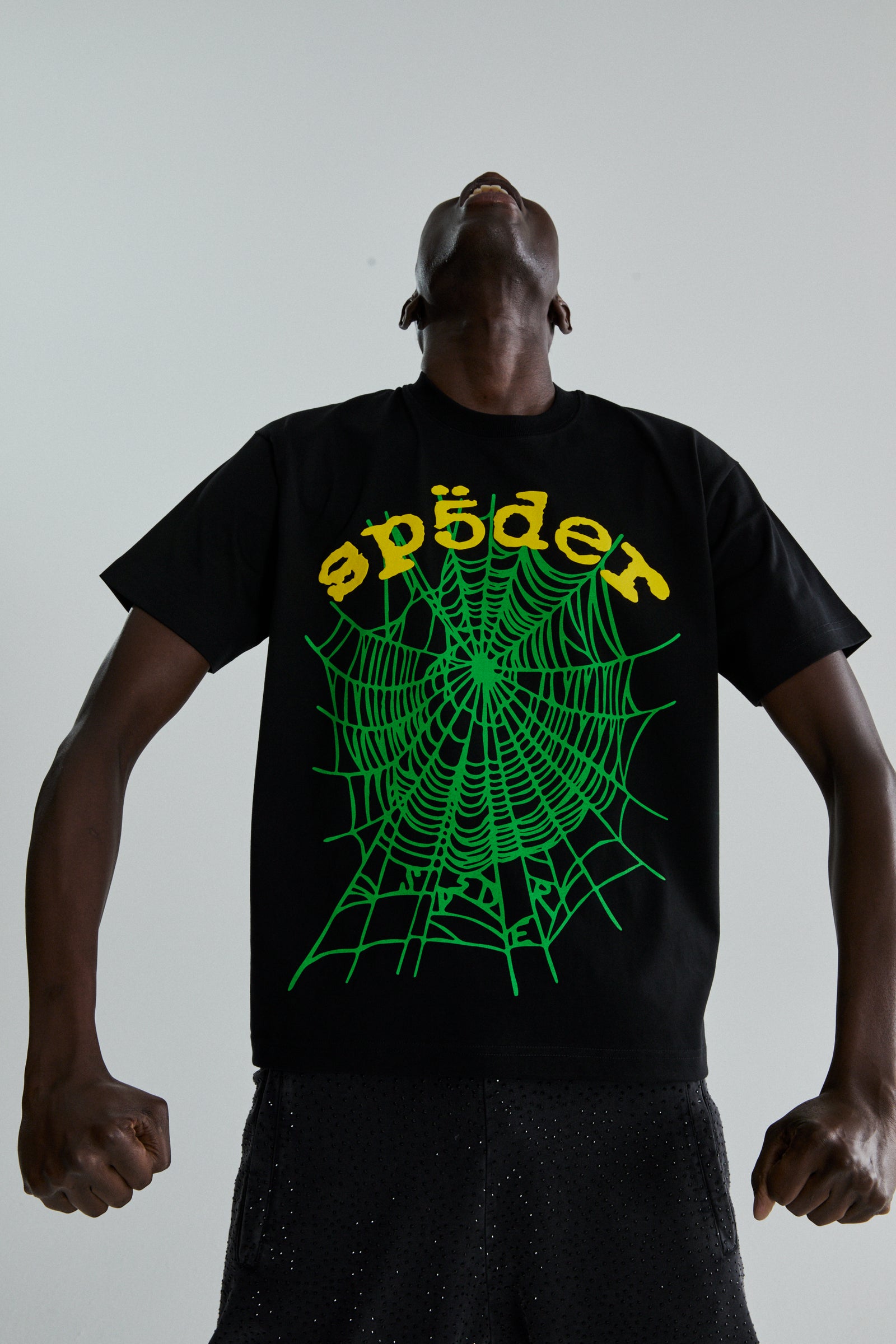 Black cotton OG WEB V2 tee with green spiderweb and yellow "sp5der" puff print, worn by a person looking up.