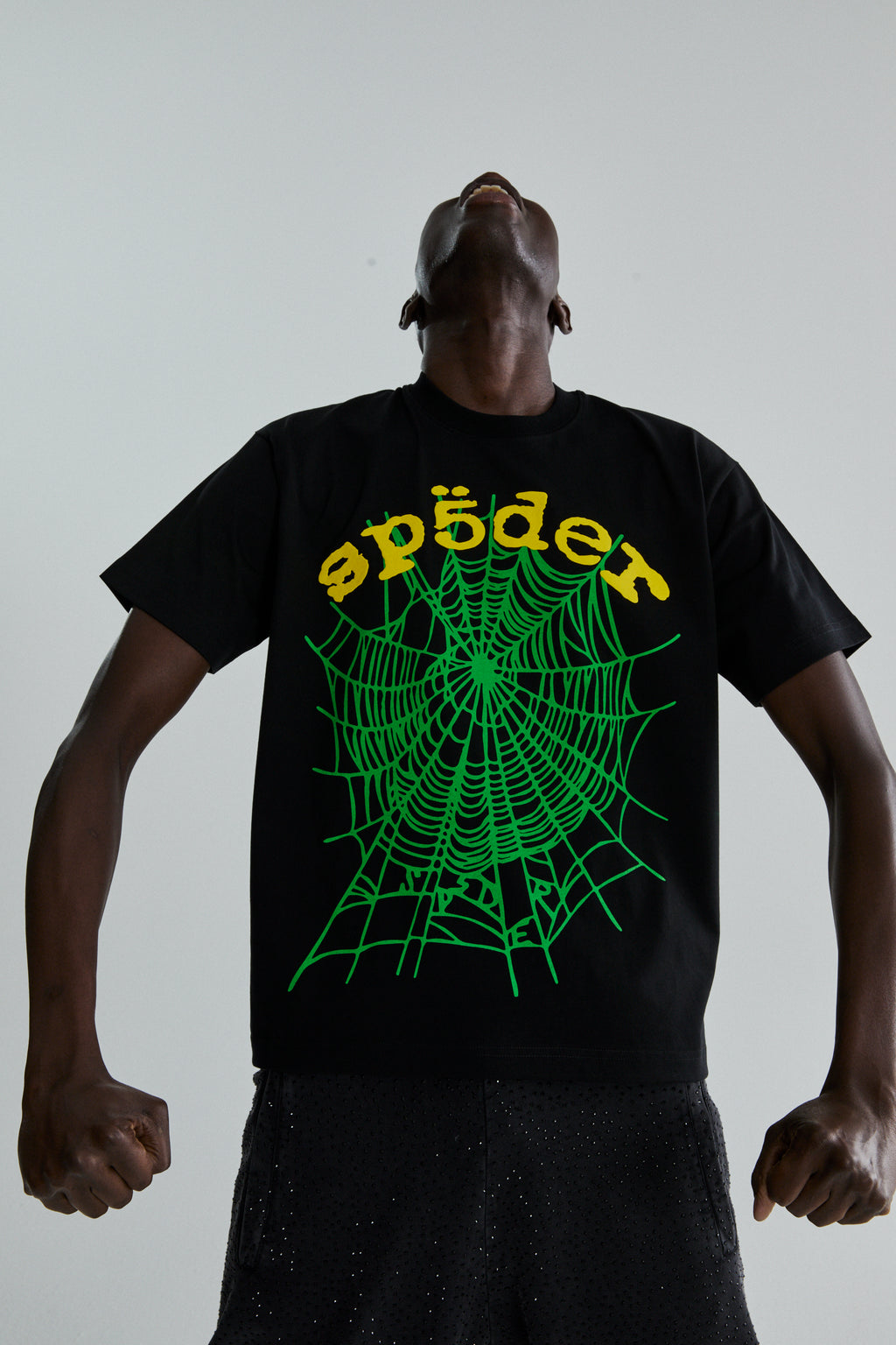 Black cotton OG WEB V2 tee with green spiderweb and yellow "sp5der" puff print, worn by a person looking up.