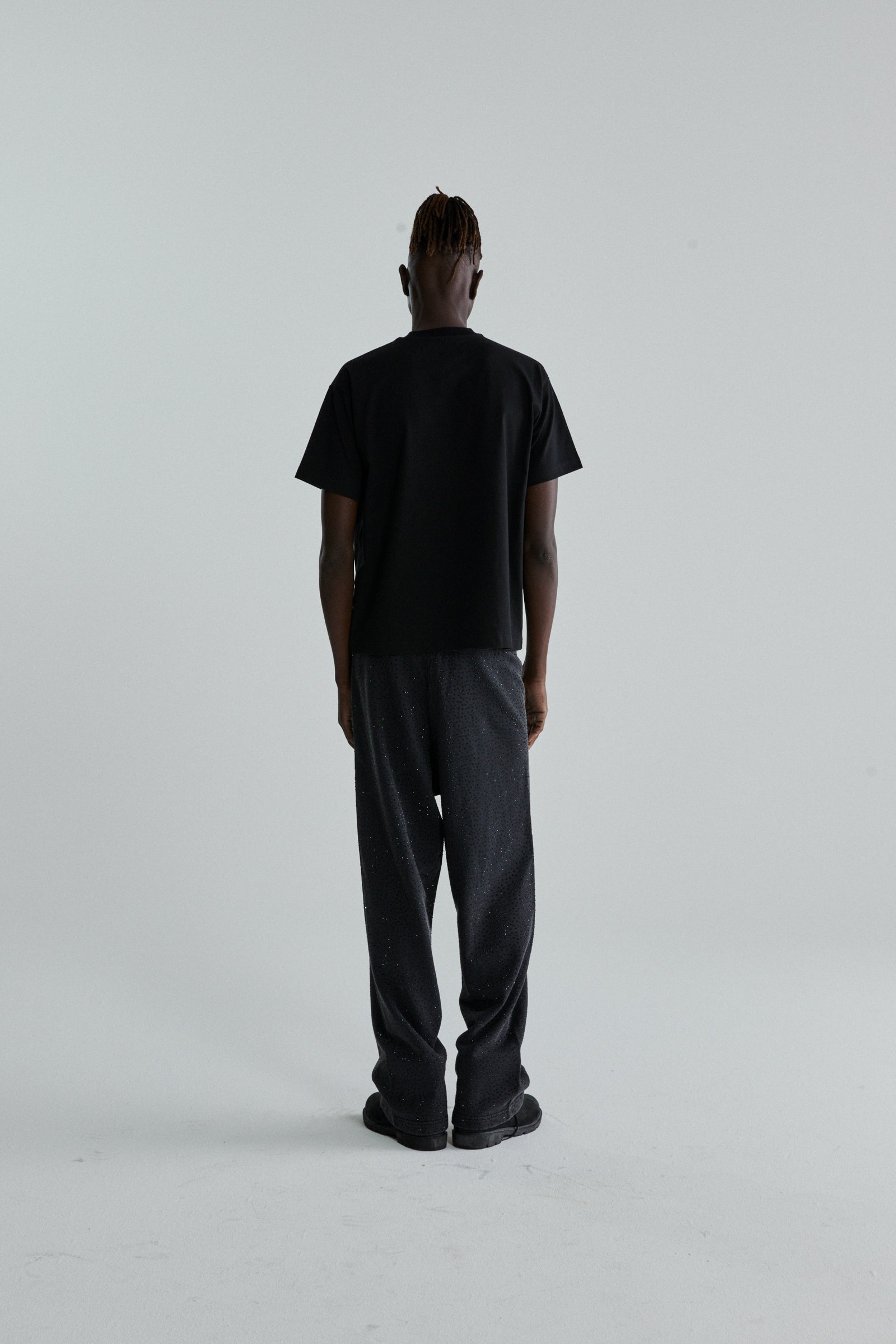 Back view of a person wearing a black OG WEB V2 TEE, a standard fit 100% cotton lightweight tee.
