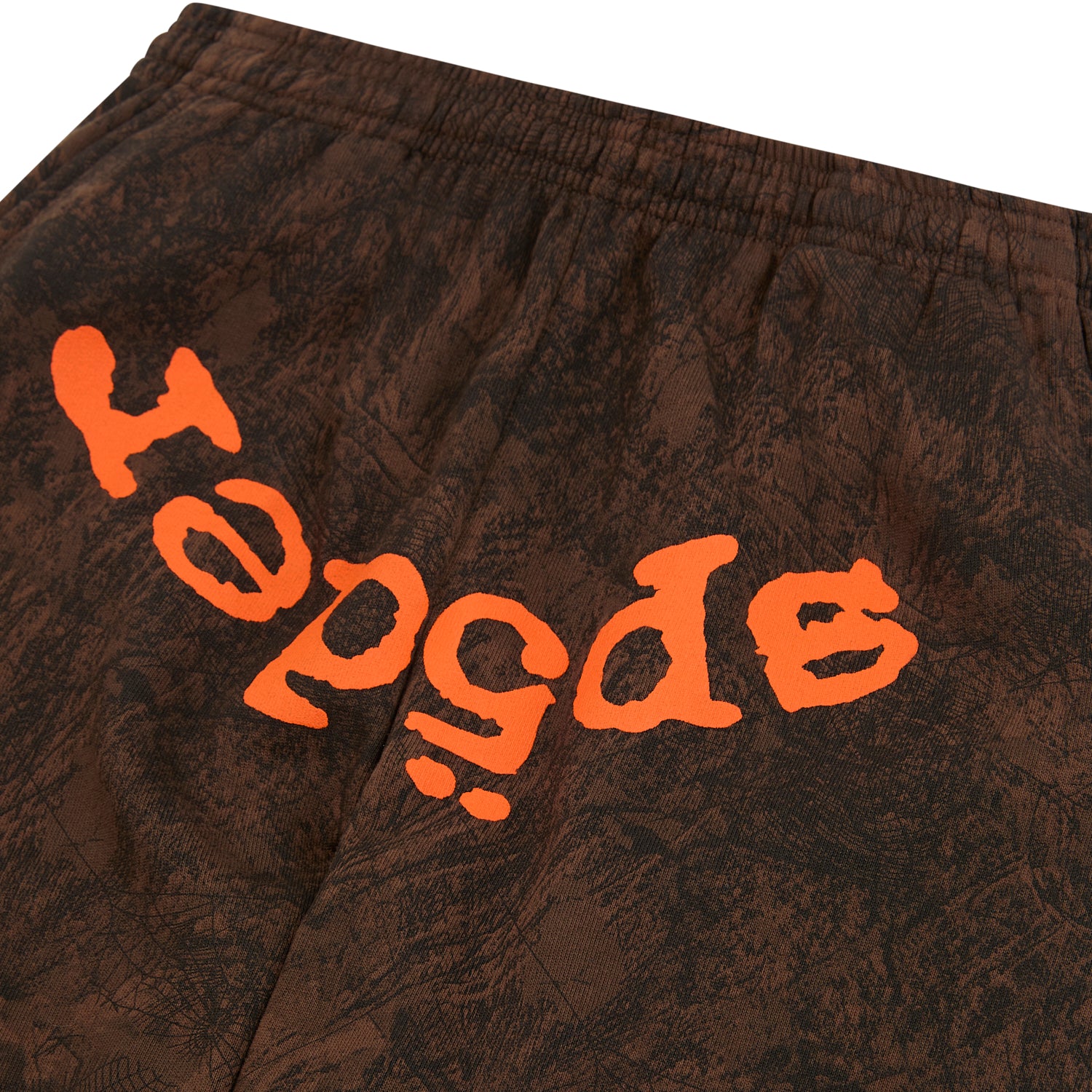 Brown tree camo sweatpants with orange "SP5DER" text at the crotch and an elastic waistband.