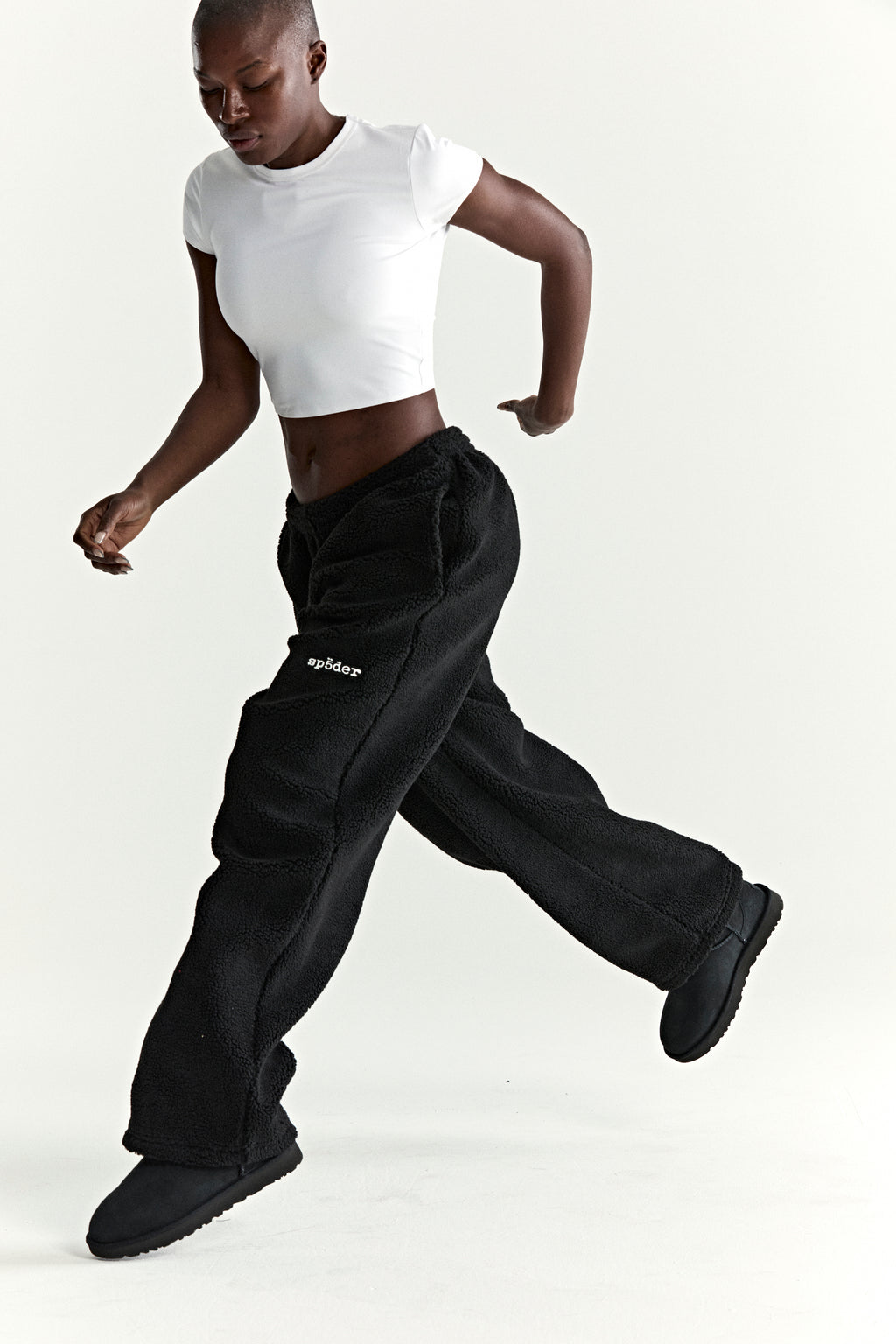 Black teddy fleece pants with rubberized logo patch, elasticized drawstring waistband, and straight leg fit.