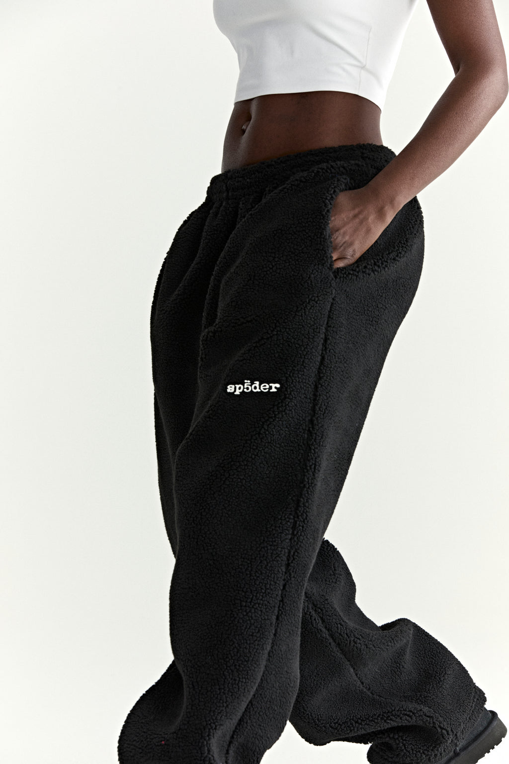 Black teddy fleece pant with white "sp5der" logo, elasticized waistband, and straight leg fit.
