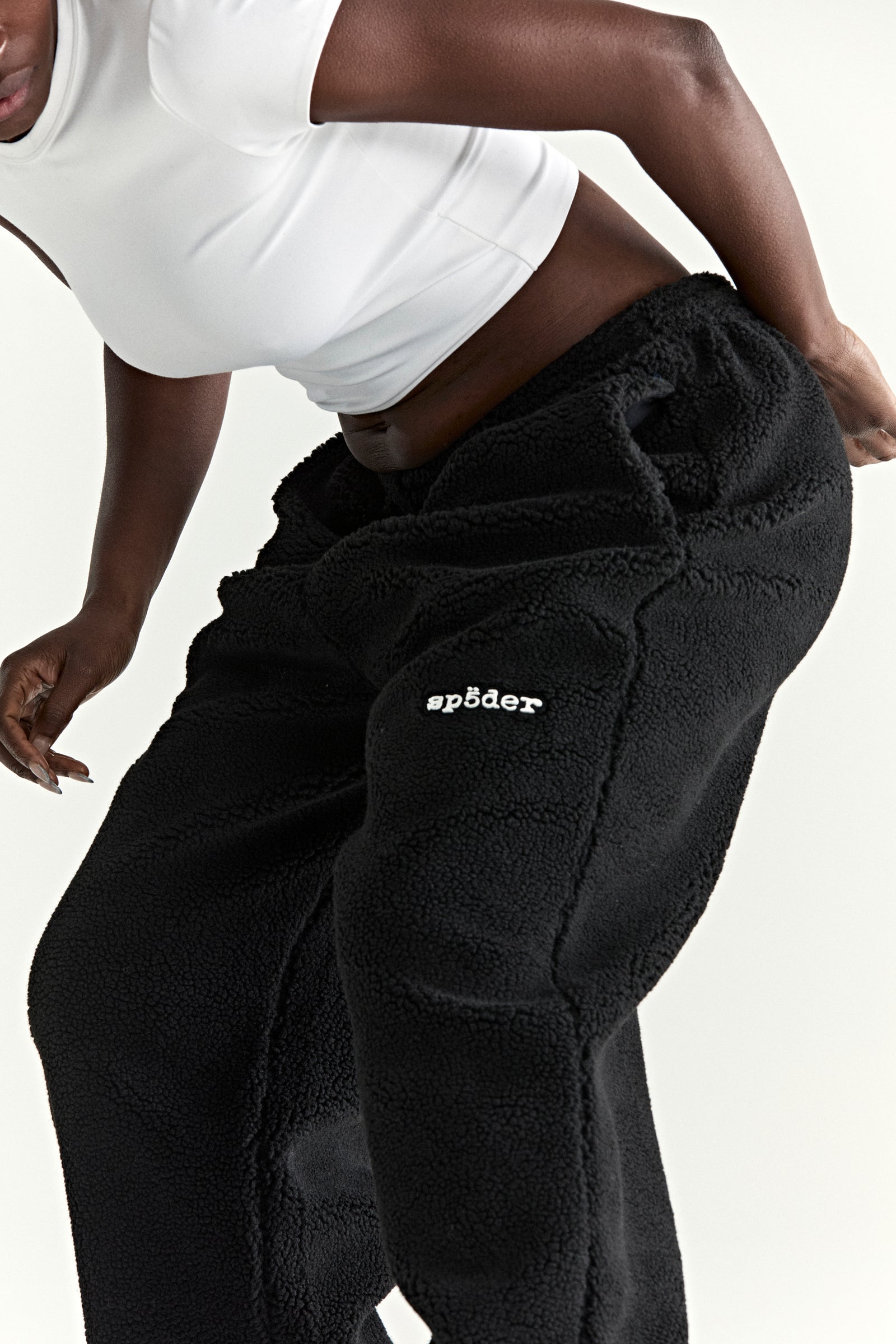 Black teddy fleece pants with white Spöeder logo patch on the leg.