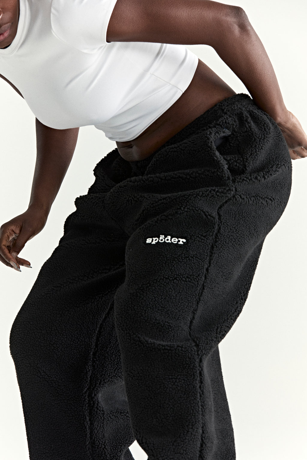 Black teddy fleece pants with white Spöeder logo patch on the leg.