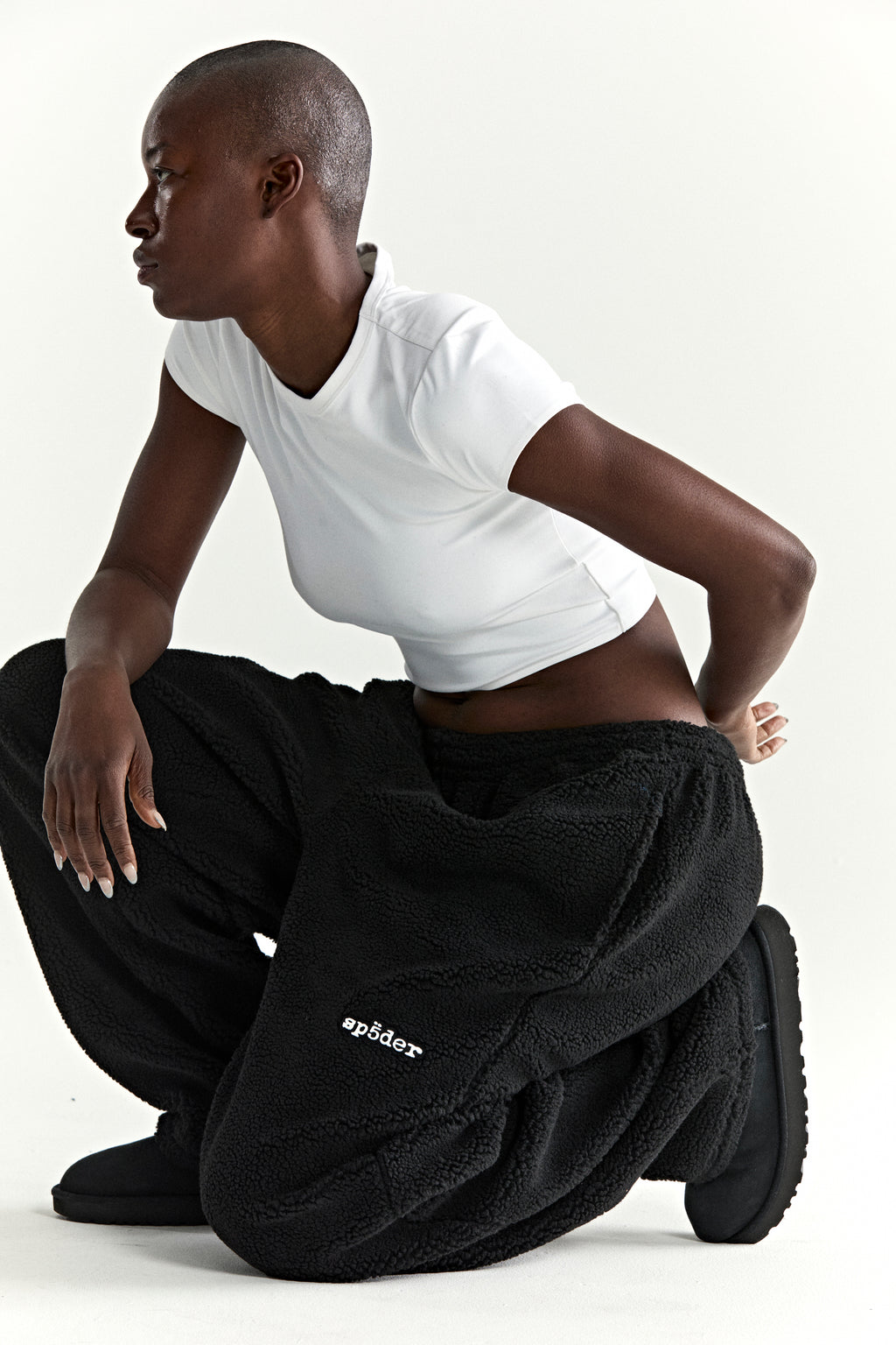 Black teddy fleece pant with rubberized logo patch on leg, worn by a model.