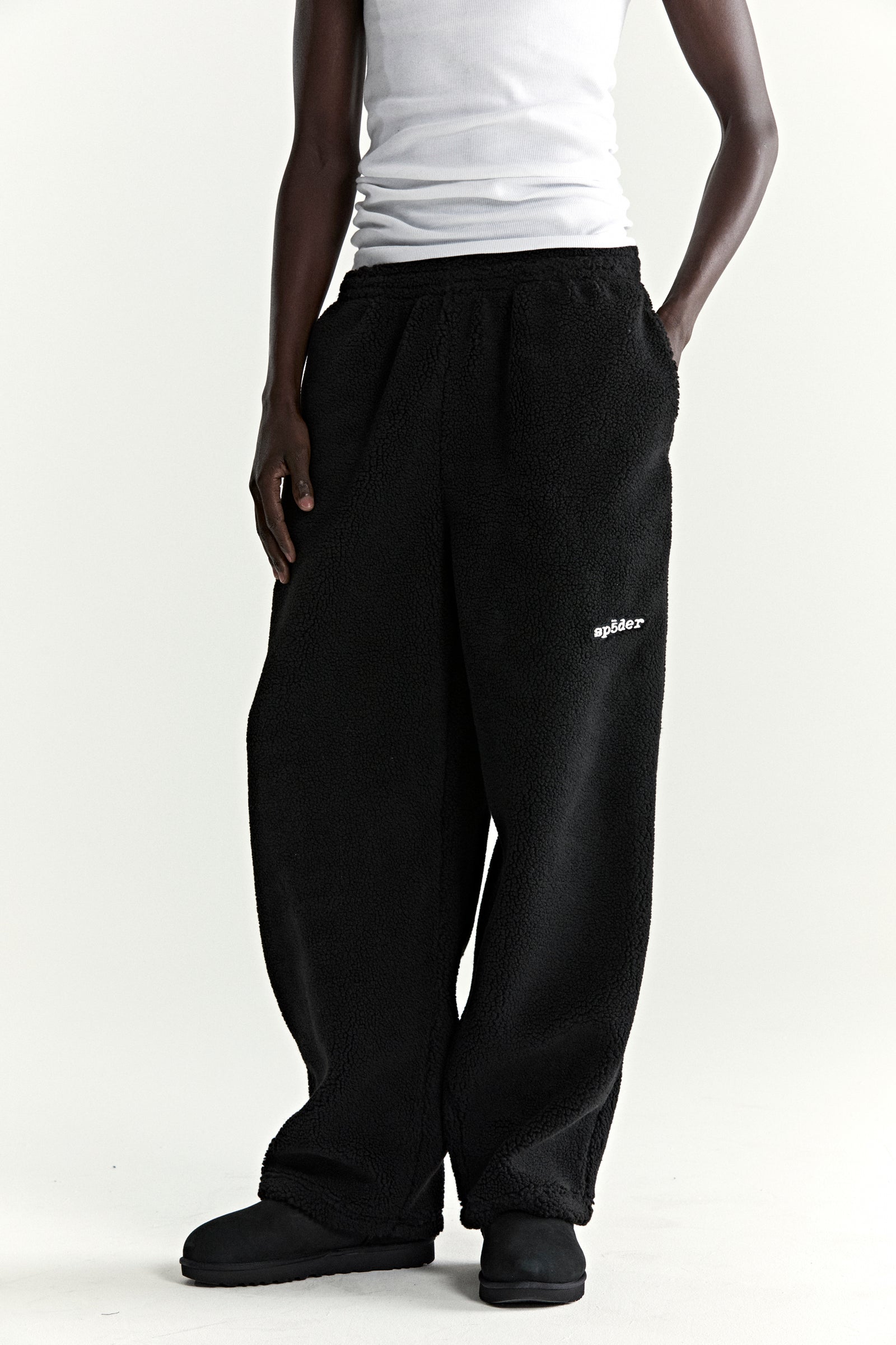 Black teddy fleece pant with white "spider" logo, elasticized waistband, and straight leg fit.